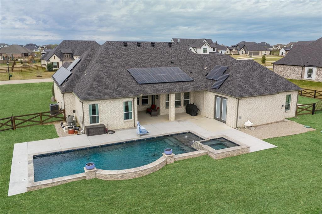 Tucked away on a full acre in Stardust Ranch, this single-story 4 bed, 3 bath home offers a rare blend of space, flexibility, and thoughtful design, highlighted by a true multi-generational suite that’s increasingly hard to find. Designed for independence and privacy, this fully equipped suite features its own kitchen, living area, bedroom, full bath, and stackable washer and dryer, along with separate access to both the driveway and backyard. At the heart of the home, the kitchen and living spaces come together in a way that feels both elevated and inviting. Custom cabinetry is paired with quartz countertops, a statement wood vent hood, patterned tile backsplash, and an oversized island that anchors the space. The living room makes a lasting impression with vaulted ceilings, exposed wood beams, built-in cabinetry, and a floor-to-ceiling stone fireplace - creating a warm and comfortable setting for everyday living or entertaining. The primary suite offers a true retreat with a tray ceiling, abundant natural light, and a spa-inspired bath featuring dual vanities, a freestanding soaking tub, and an oversized walk-in shower with bench seating. The single-story layout also offers wheelchair accessibility, making the home as functional as it is beautiful. Step outside to your private backyard retreat complete with a pool and spa, expansive patio, and plenty of room to play, garden, or simply enjoy the wide-open space of your acre lot. Automatic patio screens create a comfortable outdoor living experience year-round, while a storage shed adds additional functionality. Solar panels provide energy efficiency and long-term savings.Located in Northwest ISD and just minutes from the future HEB and upcoming commercial development, this home offers the best of quiet country living with exciting growth nearby.