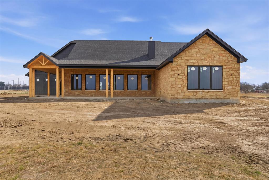 Discover refined country living on this extraordinary 20 acre estate, where contemporary design meets the tranquility of the Texas countryside offering  lifestyle opportunities that come with wide-open space—including a shop with additional living quarters and a stock tank, perfect for recreation, livestock, or simply enjoying the natural setting. A blend of luxury and thoughtful craftsmanship, with an expertly designed living space unfolding beneath dramatic plank vaulted ceilings and large windows framing expansive views that flood the home with natural light. Striking black steel double doors will open to reveal a home of exceptional craftsmanship and attention to detail. The chef's kitchen will be a showcase of luxury and functionality, featuring quartz countertops, a professional gas cooking range, black stainless steel appliances, and custom wood cabinetry throughout—designed equally for intimate family meals and entertaining. The luxurious primary suite will serve as a private sanctuary, complete with a spa-inspired bathroom featuring a soaking tub, separate tiled shower, and premium finishes. Two additional bedrooms and a versatile flex room will provide ample space for family, guests, a home office or playroom to suit your lifestyle. Beyond the main residence, the expansive acreage truly sets this property apart. The on-site shop with living space offers endless possibilities—ideal for guests, multigenerational living, a home business, or hobby space. The stock tank enhances the land’s usability and charm, providing both practical function and a scenic focal point. The expansive front porch invites leisurely mornings with sweeping views, while the outdoor kitchen and grill area sets the stage for dining and entertaining under the stars. Currently under construction, this estate presents a rare opportunity for buyer customization. Work with the builder to select finishes and personalize details, ensuring your new home reflects your unique style and vision.