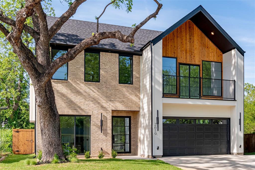 Step into this SHOWSTOPPING modern living custom residence featuring a dramatic 21-foot foyer anchored by a striking steel pivot entry door with glass panels and chevron wood flooring detail. The striking exterior is complemented by oversized horizontal picture windows with sleek black frames, a balcony adorned with cedar wood creating a bold architectural presence. Massive floor to ceiling windows throughout that fill the home with natural light. Inside, enjoy natural-finish white oak hardwood floors throughout and an open-concept layout. The chef’s kitchen offers a waterfall quartz island, floor-to-ceiling cabinetry, white oak accents, walk-in pantry, and a professional-grade stove. Designer under-stair wine storage with a glass enclosure that doubles as a statement feature.Spacious living and dining areas feature nearly 12-ft ceilings and a modern electric fireplace with porcelain tile surround. Primary suite includes cathedral ceilings, expansive windows, and a spa-inspired bath with freestanding tub, oversized walk-in shower with dual heads, and custom walk-in closet. A front studio with full bath provides flexible space for office or guests. Upstairs features a second living area, additional bedrooms—including one with cathedral ceilings and private balcony—and a full bath. Enjoy outdoor living with a covered patio, built-in grill, sink, and outdoor kitchen. Additional highlights include a 3-car tandem garage, tankless water heater, foam insulation, solid wood interior doors, high-end fixtures, and irrigation system. Located in the heart of Oak Cliff, just minutes from Downtown Dallas and the Bishop Arts District—offering the perfect blend of convenience and culture.