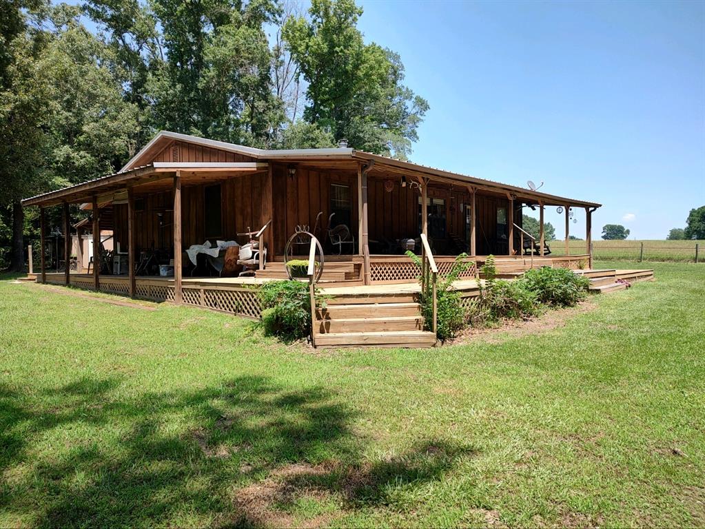 Seller related to agent. This gorgeous property sits on 4 acres, creek bottom soil that has always yielded abundant produce, good deer, hog, and predator hunting. Variety of trees, property is fully fenced and also cross-fenced. House is a 3 bedroom, 2 bath split floor plan with vaulted living room ceiling, freestanding wood stove, open living, dining, and kitchen area. 2 water heaters, knotted pine ceilings throughout. Pine is from Satterwhite Log Homes in Longview. Outside siding is cedar. Covered porches on 3 sides. 8 outdoor storage units, Quonset hay barn, 40 X 30 shop with electricity, 2 rollup doors, 1 walk-through door, 3-car carport with loft and attached shedrow, and lots more! Additional 55.644 available. Buyers and-or buyers agent to verify square footage, measurements, acreage, and schools.