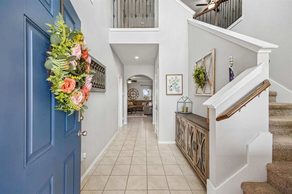 Beautifully maintained 5-bedroom, 2.5-bath home located in the highly sought-after Trails at Riverstone community in fast-growing Princeton! This inviting home offers exceptional curb appeal with stone hardscaping surrounding the front flower bed and tree, plus a charming covered front porch perfect for relaxing outdoors. Step inside to a soaring, welcoming entry featuring upgraded light fixtures and easy-to-maintain tile flooring throughout the main living areas. The spacious family room is filled with natural light from large windows overlooking the expansive flat backyard with lush, beautifully maintained grass. The open-concept eat-in kitchen is designed for both everyday living and entertaining, complete with granite countertops, stainless steel appliances, abundant cabinetry, a large island with counter-height breakfast bar seating, pantry, and adjacent utility room with built-in storage. Enjoy true outdoor living with the extended patio featuring a wood patio cover, wall-mounted television, and open grilling area—ideal for entertaining year-round. The private primary suite is conveniently located on the main level and includes an attached sitting room or office space, large walk-in closet, upgraded tile shower, and excellent storage. A stylish half bath with upgraded vanity is also located downstairs. Upstairs offers four generously sized secondary bedrooms, a spacious loft living area, and upgraded black iron stair railings for a modern touch. Additional updates include a 2023 roof, Ring security system, upgraded entry and kitchen lighting, and gutters. Residents of Trails at Riverstone enjoy outstanding community amenities including a large resort-style pool with wet play area, playground, and shaded picnic and relaxation spaces. This move-in ready home combines comfort, functionality, and fantastic community living in one incredible package