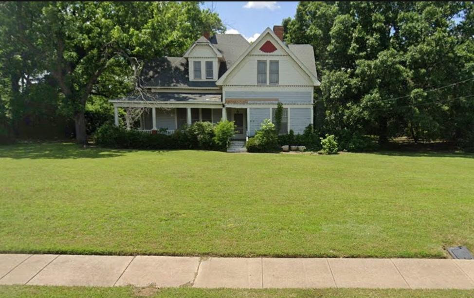Gorgeous 3924 square foot home built in 1907 arranged beautifully on 1.3728 acres with a 45' wrap around porch located just blocks south of the very sought after downtown Grandview, Texas! Features one very large downstairs primary bedroom with a fireplace, large ensuite, and walk in closet, 4 upstairs bedrooms, 2 additional bathrooms, massive living room, parlor, den, upstairs common area, sunroom, 2 mud rooms, formal dining room, and large kitchen. All original hardwood trim, doors, & floors along with a breathtaking staircase. Situated on this large corner lot is also a 12 X 20 carriage house, 14 X 20 workshop, 16 X 20 storage building, and a 24 X 24 two car attached garage. In my opinion it could be one of the most beautiful properties in Grandview, Texas. It would with some work make a terrific single-family home, bed and breakfast, or wedding venue. It is a must see! Book your showings now while it's still available!!!!