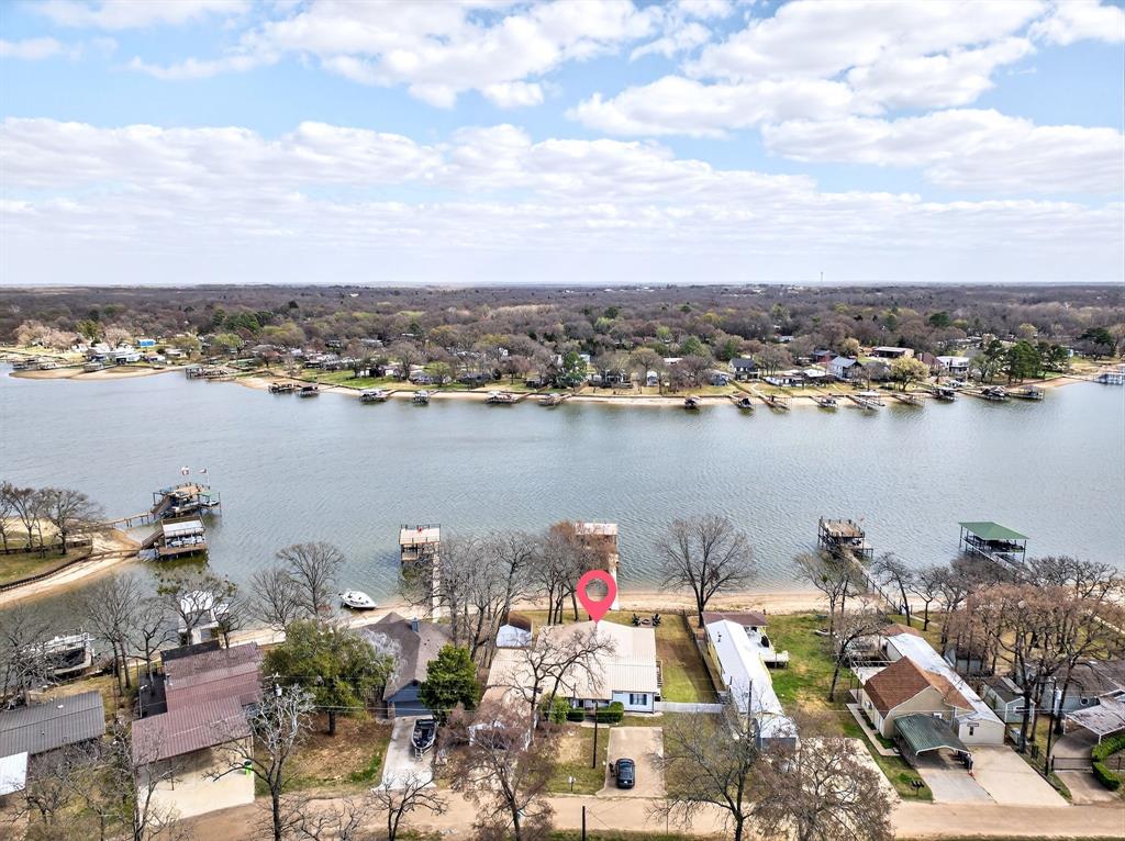 Fully furnished with open water view, this 2,100 sq ft waterfront lake house sits on 0.27 acres and delivers immediate enjoyment with strong short-term rental potential. Step into a welcoming living room that feels bright and open, creating an inviting place to unwind after a full day on the water. The kitchen offers abundant cabinetry, generous counterspace, plenty of natural light, and a central island that keeps everyone connected while cooking or hosting. The spacious ensuite primary bedroom provides a relaxing retreat with a large bath and dual vanities, while two additional bedrooms offer comfortable space for guests. Outside, a covered wrap-around deck captures beautiful open water views and overlooks a backyard ready for evenings around the fire pit, with a hot tub tucked neatly into the porch for relaxing nights. The private boat dock was rebuilt with new wood in 2025 and still holds water even when the lake is down, making lake access easy year-round. A two-car garage and additional storage building provide space for equipment and toys. Even better, the boat, jet ski, trailer, kayak, water toys, and furnishings convey, making this a true Airbnb-ready getaway. Located in Mabank roughly an hour from Dallas with an HOA community pool nearby. Cedar Creek Lake is one of the largest lakes in Texas, celebrated for its recreational lifestyle and bass fishing. Proudly Claim Your Piece of Texas!