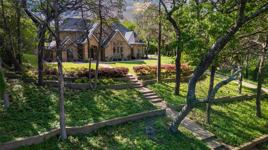 Welcome to your private retreat in the highly sought-after Frost Farms community! Situated on over 1.24 acres, this custom all-brick home offers 5 bedrooms, 4 full bathrooms, and over 3,200 square feet, perfect for those seeking space, privacy, and an acreage property near the Dallas area. The open-concept layout features vaulted ceilings, abundant natural light, hardwood flooring in high-traffic areas, and two wood-burning fireplaces, creating a warm and inviting atmosphere. The kitchen includes double ovens, an electric cooktop, and ample cabinetry, ideal for entertaining and everyday living. A private guest suite with its own ensuite bath makes this home perfect for multigenerational living or extended stays. Upstairs bedrooms include a functional Jack-and-Jill bathroom layout. Enjoy outdoor living on a covered patio with flagstone accents, overlooking a spacious backyard surrounded by mature trees, offering privacy and room to relax or entertain. Additional features include a 3-car garage with side entry, extended driveway, and a 3-zone HVAC system for comfort and efficiency. Conveniently located with easy access to major highways, this home offers the perfect balance of country-style living with city convenience.