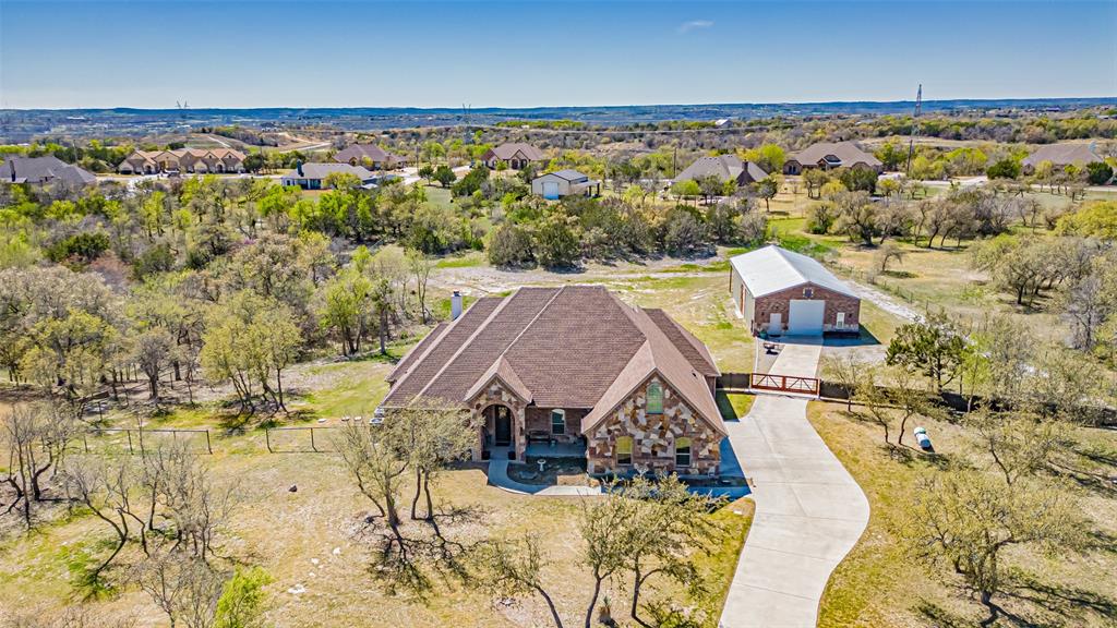 Make the drive out to see this beautiful home in Azle, Texas!  This 114 Woodlot Lane property is a single-family home located within the Deer Ridge Estates Subdivision. Built in 2015, this residence offers 5 bedrooms with all walk-in-closets and 3.5 bathrooms. The master bathroom holds a 48 inch master soaker tub! The entire home is approximately 3,160 square feet of living space. The property sits on a 2-acre lot, providing ample outdoor space. Key features of the home include a kitchen equipped with granite countertops, an island, breakfast bar, coffee bar and propane stove top! This home makes it ideal for both daily living and entertaining! The living Room features a focal point rock fireplace, creating a cozy and inviting atmosphere! The Master Suite is an oversized master bedroom that boasts a three-level molded tray ceiling. The master bath includes a spacious walk-in closet with a unique built-in vanity. Outdoor Amenities: A private outdoor kitchen is accessible via the back porch and space for a family barbeque cookout! Additional highlights of the property are a 50 x 30 workshop equipped with electricity, water and 10 X 12 roll bay doors.  The Workshop also has attached carport, offering versatile storage and workspace options, that can park a 45ft RV.  There is a RV Hook up with electricity. Garage: A three-car garage provides ample parking and storage space. water Softener installed and Roof is 9 years old.  The Deer Ridge Estates subdivision offers gated access and perimeter fencing, ensuring privacy and security for residents!