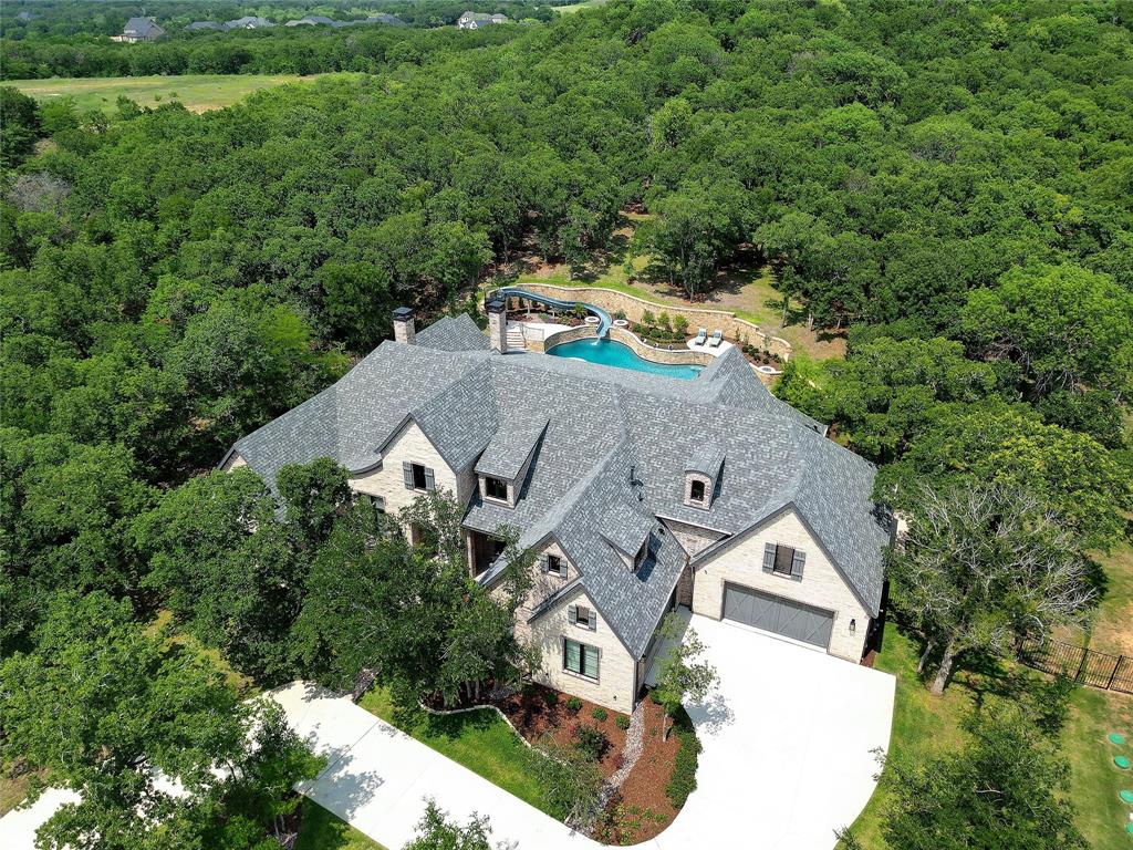 Step into this impeccably crafted custom single-story residence, showcasing an array of luxurious upgrades at every turn! As you make your entrance from the circular driveway and brick walkway, you'll be greeted by expansive wood flooring and abundant natural light that fills the great room. The striking lighted ceiling treatment in the living area further enhances the home's wonderful ambiance. Seamless transitions lead from the dining area to the breathtaking kitchen, complete with a generously sized island, top-of-the-line Wolf & SubZero appliances, and every convenience imaginable! Retreat to the primary suite where black-out drapes and spa-like bath await. Outside, the expansive 44x21 loggia beckons with its masonry fireplace, automatic screens, gas lanterns, and outdoor kitchen—a perfect setting to enjoy Texas sunsets. The magnificent backyard features a Claffey pool and spa, fire bowls, water features, and a thrilling Dolphin water slide!  A true masterpiece that won't last!