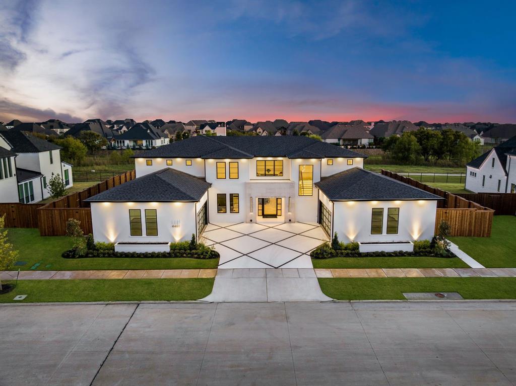 An architectural statement on a half acre greenbelt homesite, this never-lived-in Shaddock Custom Home blends modern design with livability. Positioned in The Pinnacle at Windsong Ranch, this residence offers privacy and panoramic views within one of Prosper’s top communities. Located in Prosper ISD and minutes from the PGA Headquarters, it combines contemporary architecture with high-end functionality. The modern stucco façade and stone entryway lead through a custom oversized pivot door into a bright interior. Notable for the automotive enthusiast are two oversized garages with six car capacity, sleek glass-paneled doors, RGB Smart LED lighting, optional car lift, and extra storage. Inside, white oak floors, soaring ceilings, and a 72-inch quartzite fireplace define the open-concept living area. The chef’s kitchen features Taj Mahal quartzite countertops, custom white oak wood cabinetry, waterfall island, and Wolf and Sub-Zero appliances, including a built-in Sub-Zero refrigerator, dual Cove dishwashers, pot filler, and wine fridge. Designer lighting, integrated cabinet illumination, and a whole-home water filtration system hook-up ready. This home offers four ensuite bedrooms plus a powder bath. The main level includes a secondary bedroom, private study, indoor-outdoor fitness studio, and flex room ideal for a playroom or media lounge. Upstairs, the primary suite offers a modern fireplace, custom walk-in closet, and a spa bath with a wet room, dual showerheads, and floating vanity. Two additional bedrooms and a bonus room complete the upper level. Outdoor living includes a covered patio, motorized Phantom screens, and a backyard backing to a greenbelt with room for a custom pool. Additional features include a Reme Halo Air Purification System, surround sound hook-up, and a laundry suite. Windsong Ranch residents enjoy resort-style amenities including the crystal-clear lagoon, multiple pools, fitness center, tennis and pickleball courts, parks, and scenic trails.
