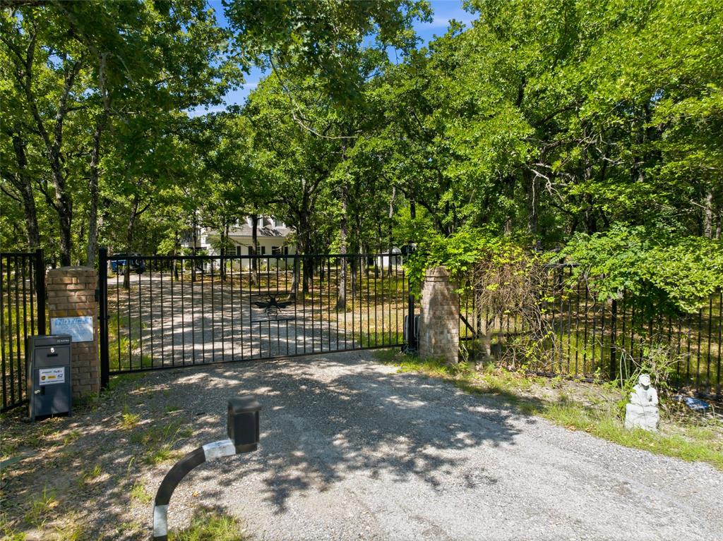 NEW PRICE ADJUSTMENT!  DON'T MISS THIS OPPORTUNITY!!  Nestled on 4.23 beautifully treed acres, this one-of-a-kind property offers the perfect blend of privacy, functionality, and rustic charm. Fully fenced with a security gate, the property features a spacious barndominium, guest house, workshop, and a serene pond—creating an ideal retreat for both everyday living and entertaining.
The impressive 5,000 sq ft barndominium is thoughtfully designed with 2,500 sq ft on the main level, showcasing an open-concept layout with durable concrete floors, a well-appointed kitchen, and generous dining and living areas. The main floor also includes a bedroom, full bath, and a large utility room. Upstairs, an additional 2,500 sq ft of open space offers incredible flexibility, complete with a bathroom and laundry area already set up for a washer and dryer and ready for a custom shower—perfect for future expansion or personalization.
Car enthusiasts, hobbyists, or business owners will appreciate the 2,500 sq ft, 4-car garage-workshop, featuring a full bath, private office or potential additional bedroom, steel stairs, a hydraulic lift for second-level access, and a wood-burning stove for year-round comfort.
The charming guest house adds even more versatility, offering a kitchen and living area with a half bath on the main floor, plus a spacious upstairs bedroom with a full bath and private balcony—ideal for guests, extended family, or rental potential.
Additional highlights include a storage building with a mini-split system, a peaceful pond perfect for fishing, and expansive outdoor living spaces. The main home features a covered wraparound porch and a large balcony where you can relax and take in breathtaking sunsets, surrounded by nature and abundant wildlife.
This truly unique property delivers space, flexibility, and tranquility—an exceptional opportunity you won’t want to miss.