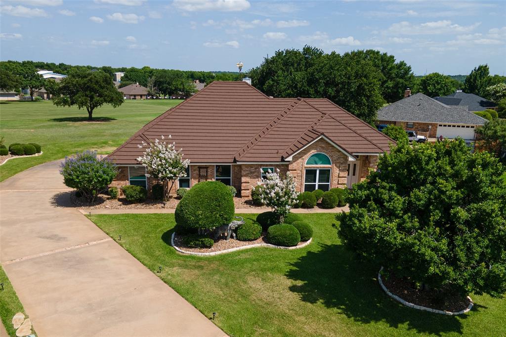 Swing into luxury with this 3-3.5-3 custom home in Pecan Plantation! Situated directly on the golf course in a quiet cul-de-sac, this home is more than a residence—it’s a lifestyle upgrade. Split bedroom floor plan. High ceilings. Stunning Brazilian redwood floors and a cozy woodburning fireplace. Kitchen offers Quartz countertops and ample storage. Includes a formal dining room, a dedicated breakfast nook, and a Flex Space for hobbies or a small office. Nice sun room, currently a game room, leads to your backyard oasis with a pergola and fenced-in lawn. Easy-care landscaping and sprinklered lawn. 3-car garage with impressive, adjacent air-conditioned workshop. Forget the stress with a high-impact metal Tek roof and a Koehler home generator. HVAC replaced in 2025. Outside trim and pergola recently painted. Enjoy around-the-clock guard-gated security, top-tier VFD & EMS, two golf courses, a marina, pools, and tennis courts. Minutes away, find the Best Historic Small Town in America—Granbury, TX—with its iconic square, art galleries, and festivals. Your retreat is only 60 minutes from the heart of Fort Worth!