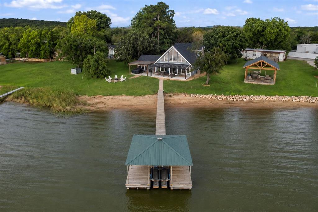 This luxuriously remodeled waterfront retreat, perfectly positioned in one of the most sought after areas of Possum Kingdom Lake, offers an exceptional blend of upscale lake living and proven income producing potential. Thoughtfully designed and impeccably updated, this turnkey property is being offered fully furnished, making it ready for immediate enjoyment or continued short term rental success. Inside, the home welcomes you with a bright and sophisticated open concept design featuring soaring vaulted ceilings, expansive windows, and a beautifully refreshed living area that seamlessly combines modern elegance with relaxed lakefront comfort. The inviting fireplace creates a warm focal point for gathering and entertaining, while the spacious layout offers effortless flow throughout the home. Recent enhancements include a stunning new back patio designed for elevated outdoor living, providing the perfect setting for entertaining guests, dining under the stars, or simply enjoying the breathtaking panoramic lake views. Upstairs, multiple flexible living and sleeping spaces comfortably accommodate family and guests alike. This property truly stands apart with its rare sandy beach frontage and newly added private boat dock, delivering direct access to the crystal clear waters of Possum Kingdom Lake and the ultimate luxury lake lifestyle. Beyond its beauty, this home is an established high performing short term rental with a strong presence on Airbnb and VRBO, offering immediate revenue potential for investors or buyers seeking a seamless turnkey opportunity. Whether you are searching for a luxury personal getaway, an income producing asset, or both, this exceptional waterfront property delivers on every level.
