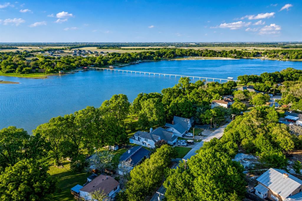 Lakefront Living on Lake Waxahachie — This recently updated 3-bedroom, 2-bath home puts you steps from the water with your own large covered dock for fishing, swimming, and boating. Inside, vaulted ceilings with exposed wood beams and a wood-burning fireplace set the tone for a space that feels both open and warm. The kitchen features granite countertops, a center island with seating, and modern finishes throughout. A charming loft built into one of the bedrooms adds character and flexible space. Outside is where this property truly shines. The fully fenced backyard is shaded by mature trees and leads down to the lake, creating a private retreat you won't find anywhere else at this price point. Gather around the impressive stone fire pit for evening breezes and stunning Texas sunsets over the water. The sloped yard is perfect for outdoor fun, and the 420-square-foot bunkhouse gives you dedicated space for guests, a workshop, or a home office. Recently updated interior plus a new roof and a new aerobic septic system—two major-ticket items already handled for you. Located in a quiet, low-traffic neighborhood in Waxahachie, you're just minutes from Highway 77 and I-35 for easy access to anything in DFW. Whether it's a weekend lake house, a full-time home, or an investment property, this one checks every box. Pictures don't do it justice—come see it for yourself!