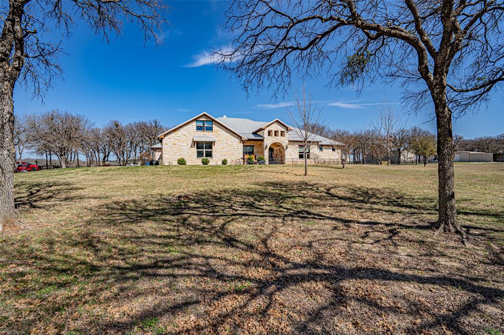 COUNTRY ESTATE! Incredible location very convenient to town. Quality best describes this 3,800 + sq. ft., 4-3-3 stone home with large bonus room.  25+ Acres, large oak trees, open pasture, corrals, impressive gated entrance, paved road, 30X60 metal barn-shop, very private. Large open living space with exposed beams, hardwood floors, gourmet kitchen, large island great for entertaining. Large outdoor kitchen area with exposed beams. Fantastic view of Comanche Peak.