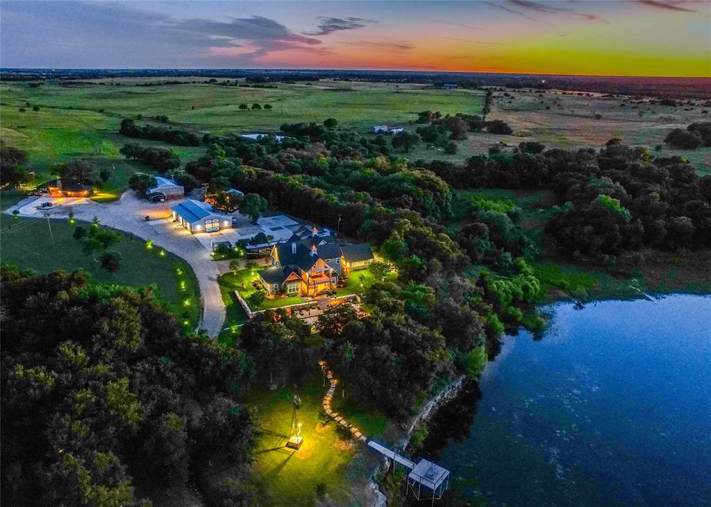 Welcome to Clear Lake Ranch in McLennan County. Located just about 18 miles from Waco and less than a mile from Valley Mills, the ranch boasts over 3,000 feet of highly desirable frontage along Highway 6. 
Improvements: 
The main residence, built in 2020, features three bedrooms and three and a half baths to include an attached garage apartment. Interior highlights include concrete countertops, a custom granite kitchen island and foam-sealed construction for year-round efficiency. The main home features 3 kitchens and 3 living rooms. Modern conveniences such as Wi-Fi–enabled thermostats, timed exterior lighting, and a comprehensive security system provide comfort and peace of mind. A private office with its own fireplace and half bath overlooks the spring-fed pond. The attached four-car garage and dedicated exercise room add further functionality. Outdoors, a resort-style swimming pool with a custom waterfall creates a peaceful retreat. Designed for self-sufficiency, the ranch includes a 48-kilowatt Generac diesel generator with a 100-gallon tank, a 1,200-foot water well, and Starlink internet service. The fully renovated guest house features granite and wood countertops, surround sound and a reinforced safe room with 10-inch concrete walls. 
Land: 
The land is fully fenced and cross-fenced into three primary pastures plus a separate house pasture. In addition to the scenic spring-fed pond, an approximately one-acre pond supports livestock and native wildlife. Ranch infrastructure includes a 60’ x 80’ main barn with a concrete slab, air lines, and water, as well as a smaller barn and an RV barn—each equipped with electricity. Multiple sprinkler systems service both residences, and a remotely controlled 360-degree camera tower allows for full-property monitoring. 
Wildlife: 
The wildlife on this property is exceptional. The lake is well stocked with bass and perch. Whitetail deer are frequently seen roaming the land while hogs occasionally pass through.