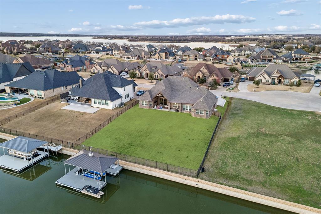 This stunning single story custom waterfront home is located in The Resort on Eagle Mountain Lake. The only 24-7 gated and guarded golf course community on Eagle Mountain Lake. Built in 2021, the home offers 4 spacious bedrooms, 4 full bathrooms, a dedicated office, and a versatile game room or flex space. The thoughtfully designed open concept layout seamlessly connects the  kitchen, dining area, and living room, where sliding glass doors frame serene canal views and create effortless indoor and outdoor living. The chef’s kitchen features marble stone countertops, a built in commercial grade refrigerator, gas range, walk in pantry, and custom cabinetry. The primary suite overlooks the water and offers a spa inspired en suite bath along with a walk in closet. A secondary master suite is located on the other side of the home with canal views, large en-suite bath and walk in closet. Two additional guest bedrooms are well appointed, one having an en-suite bath and the other convenient powder bath for visitors. The dedicated office, complete with French doors, overlooks both the living area and the canal, providing an inspiring work from home setting. The flex room currently being used as a gym has direct access to the patio as well. Step outside to a backyard ready for your vision, whether it’s a resort style pool, extended patio, or outdoor retreat. Your private boat dock includes both a boat lift and jet ski lift, making lakeside living effortless and enjoyable year round. Notable upgrades include two tankless water heaters, a circular driveway, surround sound in the living and game rooms, and custom plantation shutters throughout. Residents of The Resort enjoy unmatched amenities, including a 19-hole golf course, clubhouse with restaurant and bar, two pools, fitness center, playground, sports courts, private beach with pergolas, boat ramp, and more. This is a rare opportunity to own a waterfront property in one of Eagle Mountain Lake’s most exclusive communities.