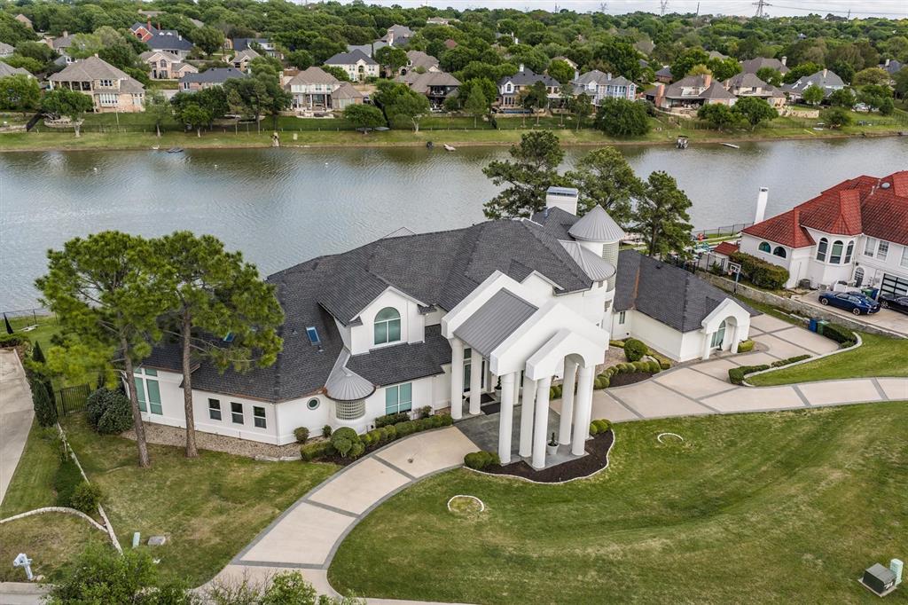 Experience luxury private lakefront living in this one-of-a-kind estate on the lake. Featuring a White House-inspired exterior and a fully reimagined modern interior home that offers an exceptional blend of elegance, comfort, and resort-style living. Originally designed for a professional athlete, the home showcases soaring ceilings, expansive windows, and an open-concept layout filled with natural light and panoramic lake views. Multiple balconies provide beautiful water views. Designer touches and high-end finishes are found throughout. The gallery-style kitchen offers extensive custom cabinetry, a large waterfall island for prep space, and a separate breakfast bar with ample seating. The home features 6 bedrooms, 4.5 bathrooms, a media room, and multiple living areas. The primary suite includes a fireplace, spa-style bath, and a glass-enclosed sauna, along with access to outdoor spaces and lake views. A standout feature is the professional media room with acoustic soundproofing, integrated disco and strobe lighting, and a custom bar with color-changing Cristallo countertops. Full-home audio and LED lighting synchronized with music create an immersive entertainment experience. Situated on a 0.79-acre lakefront lot with 7,444 square feet, the property offers direct lake access, a resort-style pool, and an outdoor kitchen. An extensive LED exterior lighting sys enhances the home’s presence at night. Enjoy boating, jet skiing, paddleboarding, and other water activities right from your backyard. Highland Village offers a strong outdoor culture with parks, trails, and a highly rated, safe community. Minutes from the Shops at Highland Village, offering upscale shopping and dining, enhancing both convenience and lifestyle. Convenient access to major FWYs, DFW international Airport, Frisco and Dallas for perfect balance of lakeside tranquility and city accessibility.