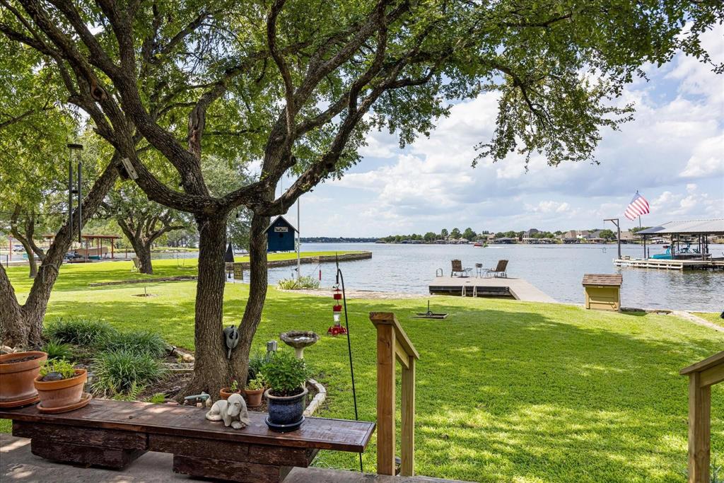 A rare find, walk-out water, on main body Lake Granbury, with deep water, a private swimming cove, spectacular views, awesome sunsets and a totally renovated lake house. This one has it all and is perfect for a vacation rental property. There is 79 feet of waterfront property to enjoy with a durable, long lasting, TREX fishing dock and a private community boat ramp. The newly renovated house has been expanded to 3581 square feet with 4 bedrooms (2 are master bedrooms and both located on the first floor), 3.5 baths plus a dedicated office. The kitchen, dining, guest lake suite and living areas all offer incredible views that are truly breathtaking! The versatile upstairs bedrooms are currently being used as a craft room and a man cave, but there are so many possibilities with the upstairs space and could be easily adapted to suit various needs. There is a model train room that could serve as an additional office or playroom. Outdoor living is gorgeous with mature pecan and oak trees, horseshoe pit and ample opportunities for fishing and swimming. The backyard is the perfect place to enjoy views of the lake, drink your coffee, entertain guests or watch the sun set with a glass of wine. This property could be your dream home on the lake, a weekend getaway or even a great short term rental investment. The guest lake suite is handicap accessible with a large closet and awesome lake view. The home offers abundant climate controlled storage, including a walk-in attic storage and a mini-split AC unit in the garage.  This property is nestled at the end of a quiet cul-de-sac. This is a truly exceptional property! Come take a look and dip your toes in the lake.