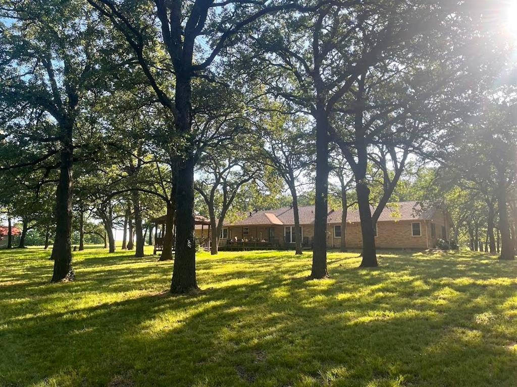 When you need to ..Getaway from the Getaway.. A private slice of Texas paradise awaits. Nestled within a mature post oak forest of many century-old trees, this beautifully remodeled country sanctuary offers the perfect blend of peaceful seclusion and modern comfort. Located just 5 minutes from Lake Texoma, approximately 18 minutes to Sherman, and 20 minutes to Gainesville, you can enjoy the tranquility of country living without sacrificing convenience. As you enter the property, you’ll appreciate the park-like setting complete with scenic views, gentle creek, two ponds, and several acres of established crimson clover that returns year after year. Deer and turkey regularly visit the property, creating a true nature-lover’s retreat. This property feels like your own private sanctuary. Inside, the home has been thoughtfully remodeled with stylish modern updates while maintaining its warm country charm. The inviting floor plan features hardwood floors, granite countertops, stainless appliances, energy-efficient windows, custom vanities, walk-in shower, and beautifully updated baths. With three generous bedrooms, two baths, formal dining, additional living or flex space, and an oversized two-car garage, there is room for everyone to spread out and enjoy. The garage also features a dedicated well pump room for added convenience. Fiber internet hookups are available, allowing you to stay connected while enjoying the peaceful surroundings.  Outdoors, the property continues to impress with two additional outbuildings perfect for storage, workshop space, hobbies, or equipment. One of the land’s most unique features is the rare Registered and certified Comanche marker trees, offering a remarkable piece of Texas history. Whether you’re sipping coffee beneath the shade of the oaks, fishing by the pond, or enjoying quiet evenings watching wildlife wander through the trees, this is the kind of property that rarely comes available. Country living truly does not get better than this