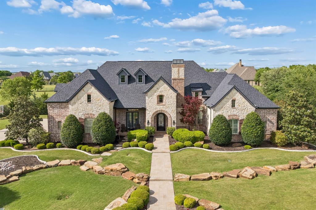 Stunning Dave R. Williams custom home in highly sought-after Prosper ISD, offering approximately 6,100 sq ft on over 1.5 acres with exceptional indoor & outdoor living. Beautiful curb appeal with extensive landscaping, circle driveway with striking rock & brick elevation-water well on property to irrigate the yard. Resort-style backyard features pool, spa & waterfall, batting cage, putting green, fire pit & expansive covered patio complete with built-in grill, large bar, outdoor refrigerator, TVs & extra storage. Dedicated pool-access powder bath adds convenience for entertaining. Thoughtfully designed floor plan includes 5 bedrooms, 5 full baths & powder bath, a private executive study with fireplace & built-ins & a spacious formal dining room. Open living area connects the kitchen, living room, breakfast nook & bar creating an ideal space for gathering. Chef’s kitchen offers a large island with wine refrigerator, gas cooktop, double ovens, built-in refrigerator, extensive cabinetry & generous counter space. Living room features stone fireplace, built-ins, high ceilings & abundant natural light. Private primary suite includes bay window sitting area & spa-inspired bath with dual vanities, oversized walk-in shower, soaking tub & separate his-and-her closets. Two additional bedrooms with en-suite baths & a dedicated media room are located downstairs. Upstairs features a large game room, wet bar, two split bedrooms each with private full bath, plus a bonus room with built-in desk & cabinetry ideal for 6th bedroom or second study or craft room. Additional flex room perfect for second media or fitness room. This home showcases luxury craftsmanship & designer finishes, including extensive wood flooring, plantation shutters, intricate custom moldings, built-ins, multiple fireplaces, soaring ceilings,  abundant natural light, extra storage, 4-car garage & additional exterior storage hidden behind fence. Exceptional property combining luxury, privacy & premier amenities.