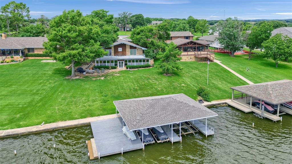 Tucked away on a private cul-de-sac just one minute from the gated community entrance, this three-bedroom lakeside retreat offers the rare balance of peaceful seclusion and everyday convenience—with no pass-through traffic to disturb the calm. Each morning begins with breathtaking sunrises shimmering across nearly 100 feet of premium shoreline, while afternoons are best enjoyed in the shade of the expansive grassy backyard—an inviting setting for lakeside gatherings, yard games, or quiet moments with a view. Inside, the home offers comfortable living spaces designed for both relaxation and connection. A versatile bonus room provides flexibility to fit your needs, whether imagined as a game room, bunk room, media space, or private guest suite. Whether you choose to embrace the nostalgia and charm of this classic 1970s lakeside retreat or envision building a custom home on this exceptional, premium lot, the possibilities here are truly remarkable. With its unbeatable location, generous shoreline, and serene setting, this property offers a rare chance to create a lakefront legacy tailored to your vision.