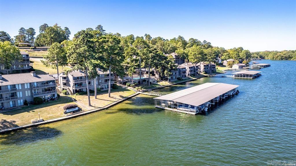 MORE than just a 3-bedroom, 3-bathroom condo - it has a fabulous game room that guests absolutely love!  Boasting and "EXCEPTIONAL" rating, a Guest Favorite, and "10 out of 10" in hundreds of reviews!!!  It is selling fully furnished and offers the perfect blend of comfort, luxury, and outdoor enjoyment. Located in a stunning lakeside location, you'll experience breathtaking views and year-round water access with your own covered boat slip.  Inside, you'll find updated and spacious living areas designed for relaxation and entertainment. A wet bar and game room make hosting guests a breeze, while the open-concept layout seamlessly connects the modern kitchen, dining, and living spaces. Each bedroom is generously sized, ensuring privacy and tranquility.  Step outside and soak in the beauty of Lake Hamilton on your two covered patios also enjoy cooking on the grilling patio. Take advantage of the community amenities, including sparkling swimming pools and tennis courts, offering endless opportunities for recreation and leisure.