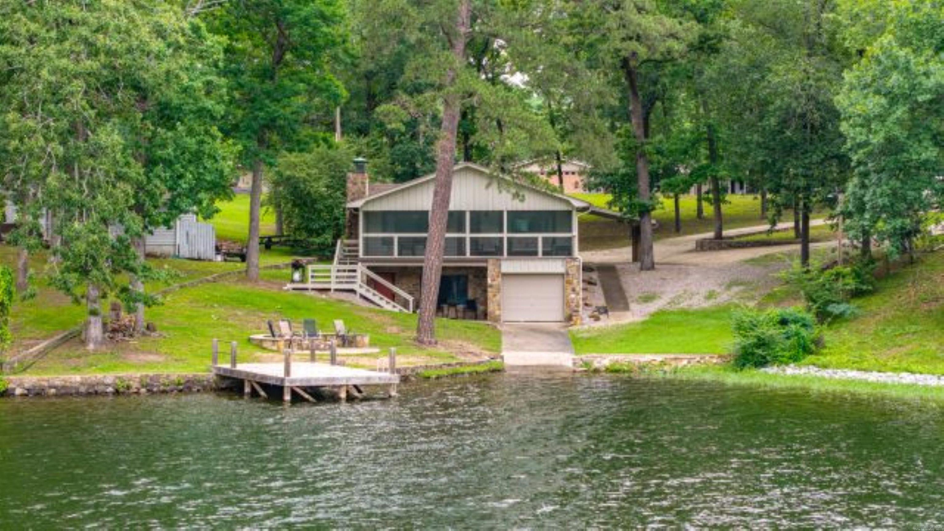 This custom-remodeled Lake Hamilton home has easy access to the water from the boat ramp and easy access to town and shopping from its central location. Located off Airport Rd. in a quiet neighborhood, the large lot affords privacy and room for activities, as well as space for possible detached ADU/garage options. The 2018-2020 remodel included a new electrical panel, plumbing, AC/heat pump, windows, and roof. Commercially installed drainage, a new driveway, and a fire pit are added bonuses! The 300 square foot screened porch offers great views and more living space. This wide inlet and the boat ramp also make the lake accessible in the fall and winter when Lake Hamilton is in drawdown status. Custom cabinetry and granite countertops make the kitchen and bathrooms beautiful and functional! The home comes fully furnished.