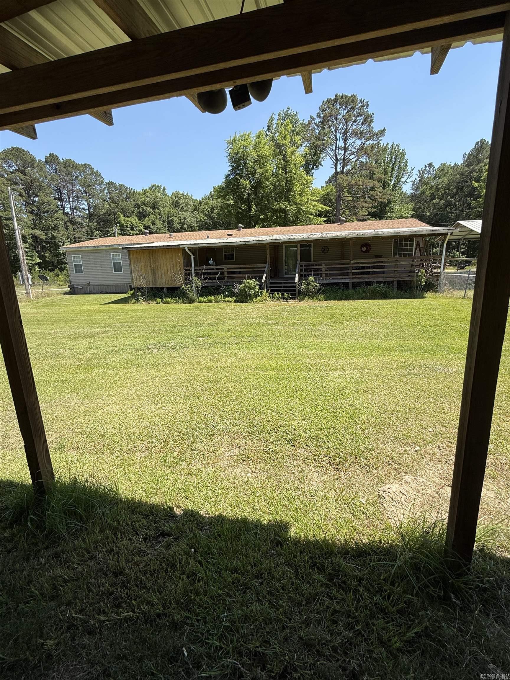 Large Open concept doublewide with add on front and back porches and storage room. 4 bedrooms and 2 living spaces provide room and comfort for all. Large kitchen and fenced backyard with St. Augustine grass provides a great area for outdoor activities and entertaining. Added building at back with overhang provides a great place for storage or workshop or could be completed for a tiny guest house. Property is being sold "As IS".
