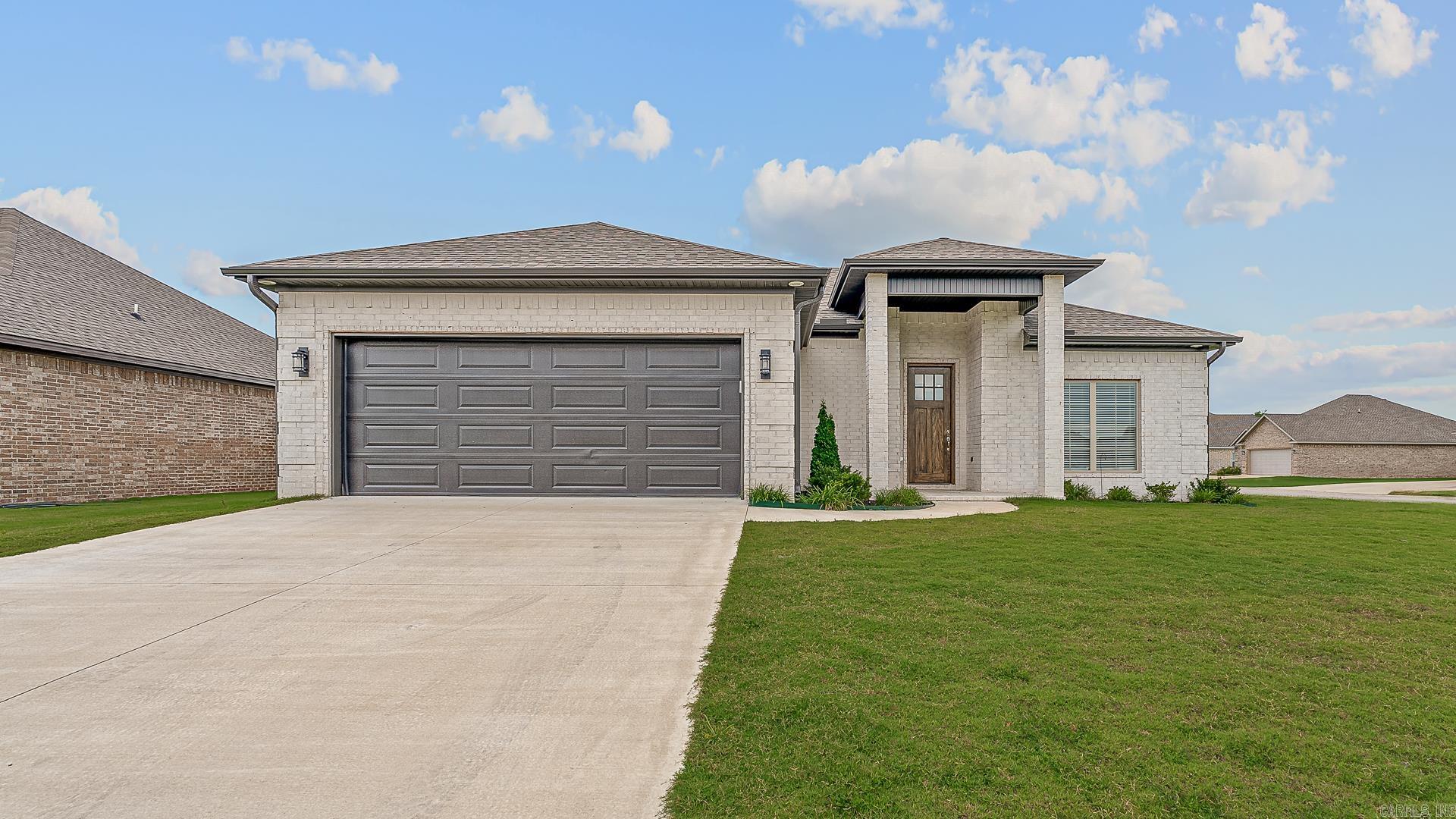 Built in 2023, this 3-bedroom, 2-bath home offers 1,441 square feet of thoughtfully designed space with a built-in saferoom, modern electric fireplace, screened-in back porch, and premium upgrades—all on a spacious corner lot. Polished, private, and perfectly positioned, this meticulously-maintained home features crisp white brick, rich laminate flooring, chrome fixtures, and an open-concept layout ideal for everyday living. The kitchen showcases granite counters, stainless appliances, a subway tile backsplash, and a large breakfast bar and kitchen island. The primary suite includes a glass walk-in shower with removable accessibility features, while the screened porch and oversized lot extend your living space outdoors. With new construction efficiency, a two-car garage, and easy access to Jonesboro, this home blends comfort, style, and smart design.