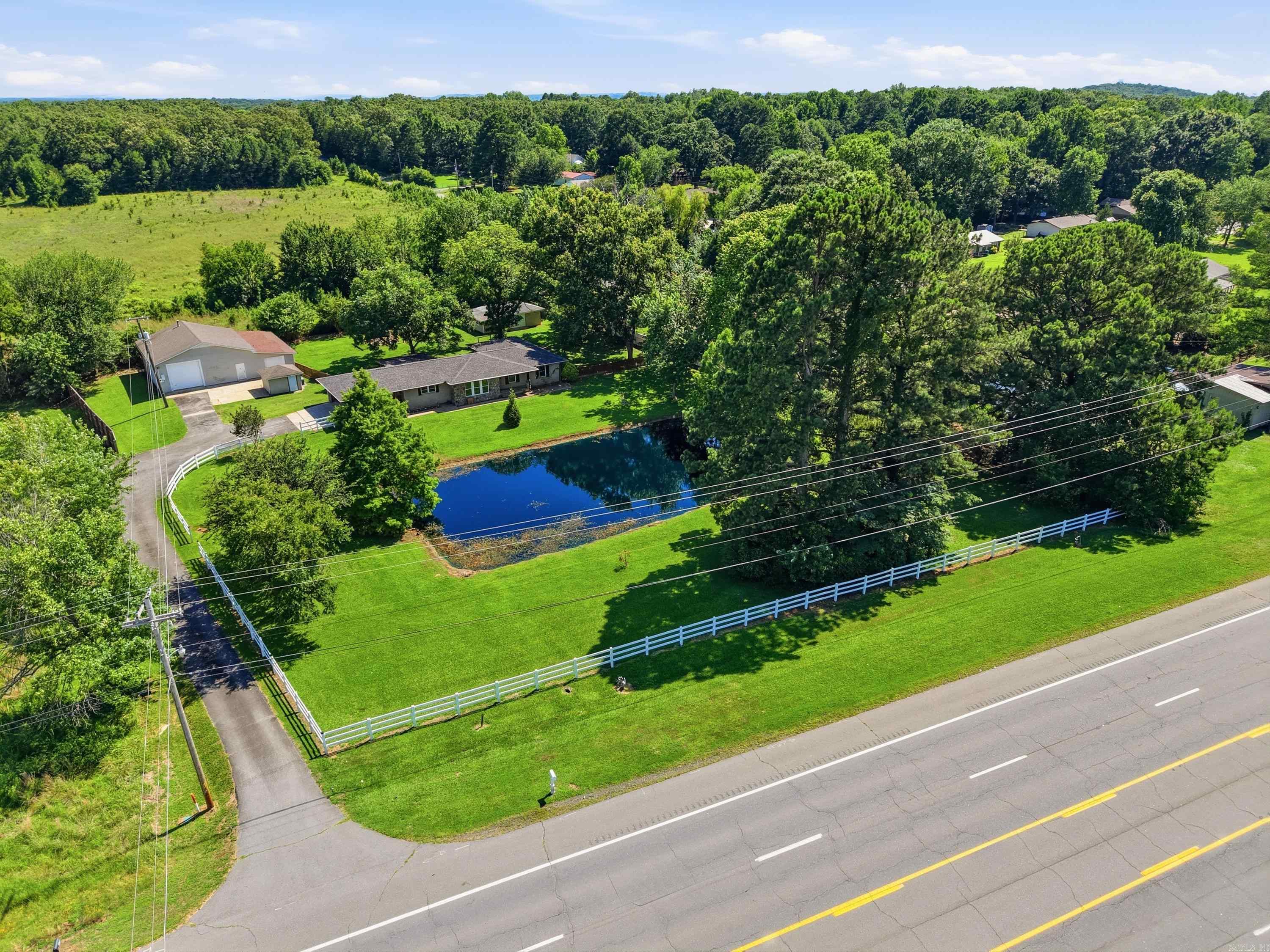 Step into this beautifully updated 3BR/2BA home on 1.83 acres in Conway! Offering 2,100+ SF of living space, this property blends modern updates with country charm. Features include waterproof vinyl flooring, a fireplace, and a stylish kitchen with unique glow-in-the-dark epoxy countertops. Enjoy peaceful views of the front pond, white vinyl fencing, a covered/gated back porch, and outdoor fireplace. Major updates completed in 2019 include roof, HVAC with ductwork, gutters with Leaf Guard, tankless water heater, updated electrical and plumbing, septic tank lines, sump pump, and a whole-house generator. All Frigidaire appliances, including the refrigerator, convey. Need space? You'll love the 51x31 shop (1,989 SF) and additional 31x19 shop (589 SF), perfect for storage, hobbies, equipment, or a workshop. Enjoy the best of both worlds—private country living with room to roam, all just minutes from Conway shopping, dining, schools, colleges, medical facilities, and easy I-40 access. Move-in ready and packed with value!