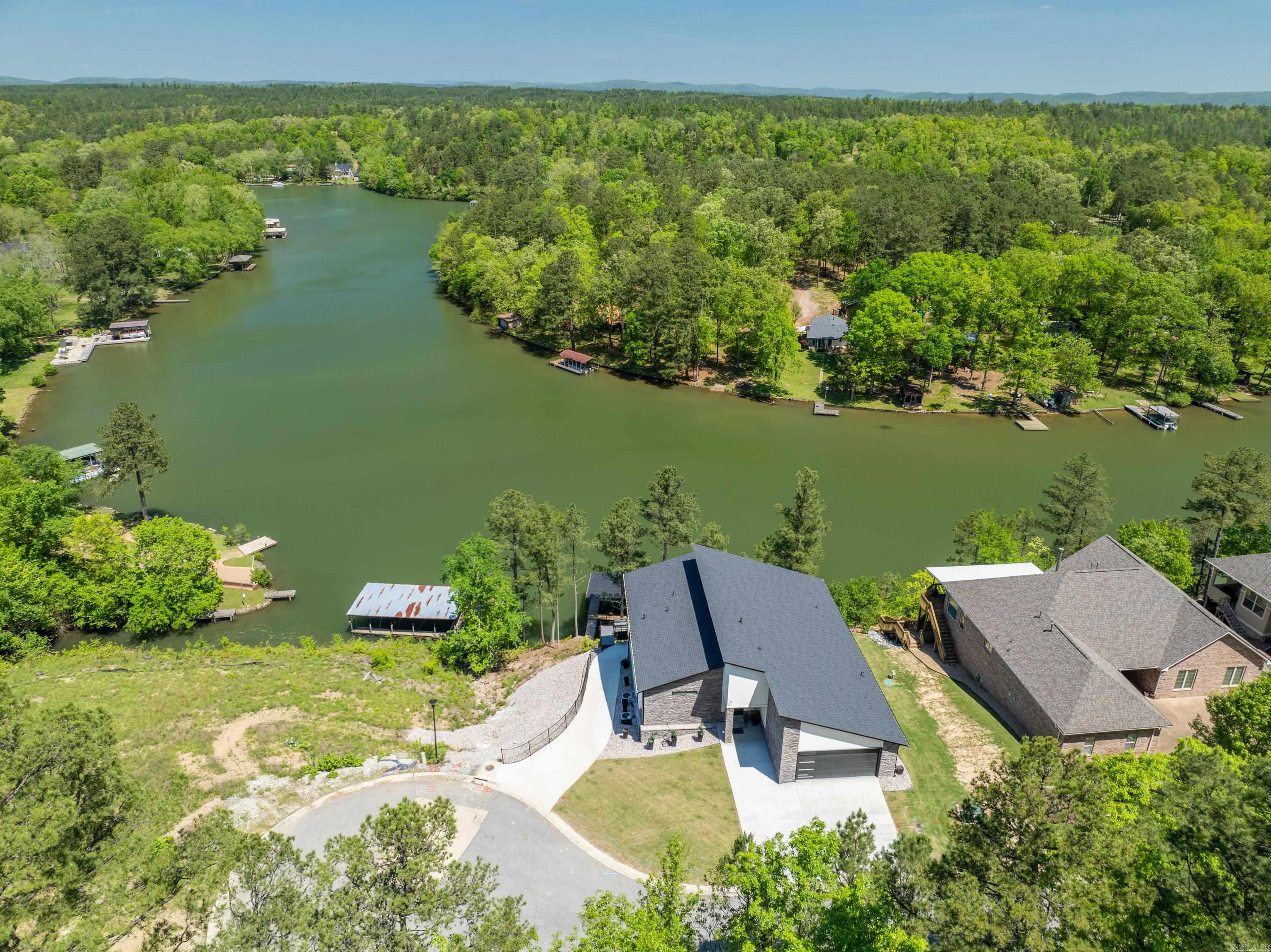 This modern contemporary lake house on Lake Hamilton is the epitome of luxury living. With its high-end finishes and attention to detail,every corner of this property exudes sophistication and style. As you step inside, you'll be greeted by breathtaking views of LakeHamilton from almost every room. The expansive windows allow natural light to flood the space, creating a bright and invitingatmosphere. The beautiful outdoor setting is highlighted by a gunite pool overlooking the serene waters of Lake Hamilton. Whetheryou're lounging by the poolside or taking a refreshing dip, you'll feel like you're living in your own private paradise. With 6 bedrooms and5 bathrooms, there's plenty of space for family and guests to relax and unwind. Each bedroom is beautifully appointed, offering apeaceful retreat after a day of lakeside adventures. Multiple living areas provide ample room for entertaining, with comfortable seatingand stunning views as the backdrop. Whether you're hosting a formal dinner party or enjoying a casual evening with friends, this home isperfect for gathering and making memories. The full kitchens on each level are a chef's dream, equipped with top-of-the-line appliancesand