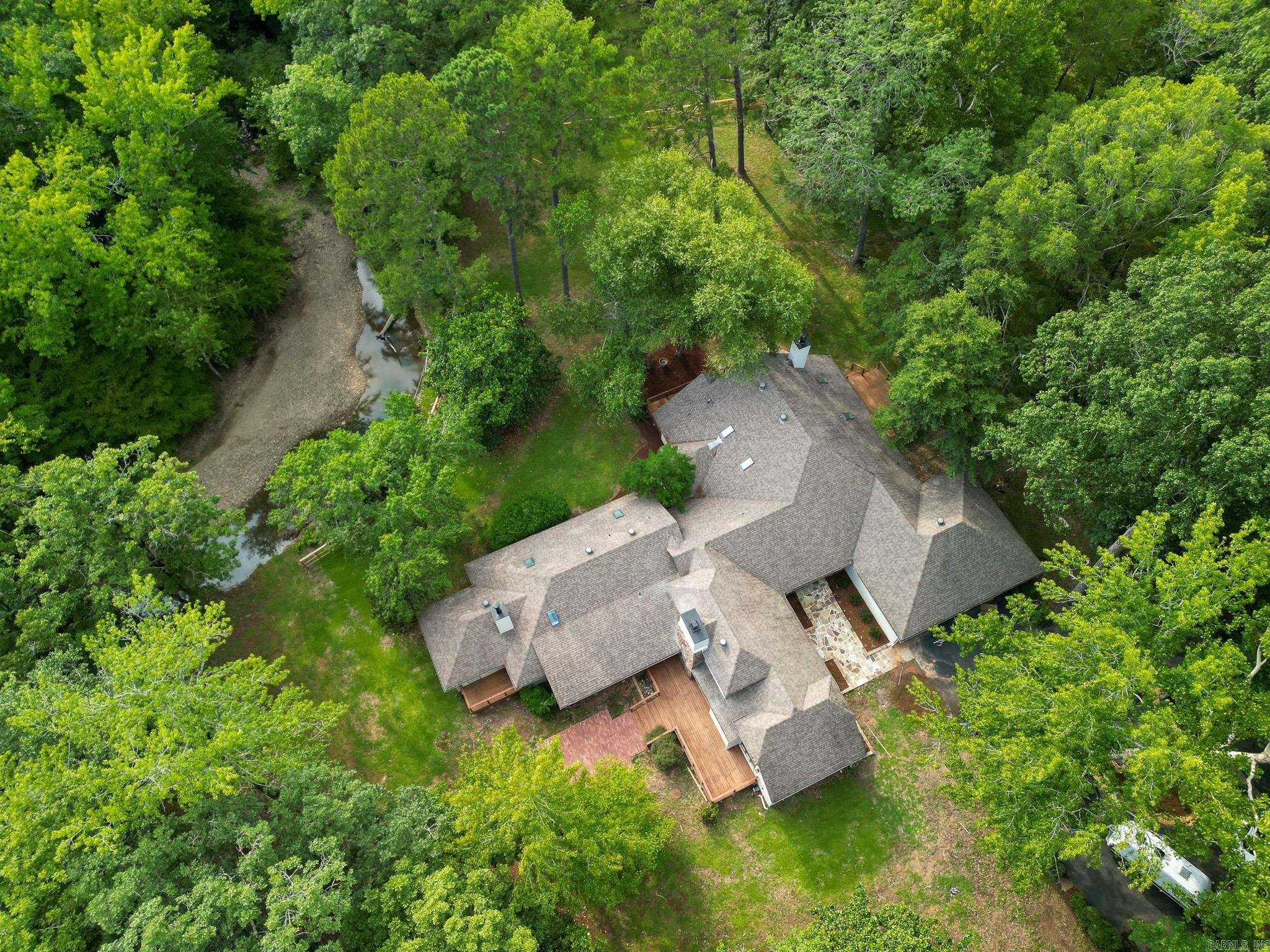 Discover peace and luxury on 10 acres with the Little Maumelle River winding through your backyard, a mountain hillside beyond the creek, and a tranquil front pasture. This 4-bedroom, 4.5-bath home has been beautifully remodeled, blending comfort with elegance. The gourmet kitchen features two islands, perfect for gathering, while three fireplaces and abundant skylights fill the home with warmth and natural light. Every bathroom has been updated with stunning tile, and the master suite is a true retreat—boasting a freestanding tub and an oversized shower with a rain shower cascading from a skylight above. Whether you’re savoring morning coffee on the porch or exploring your private riverbank, this property offers a lifestyle of serenity and sophistication.
