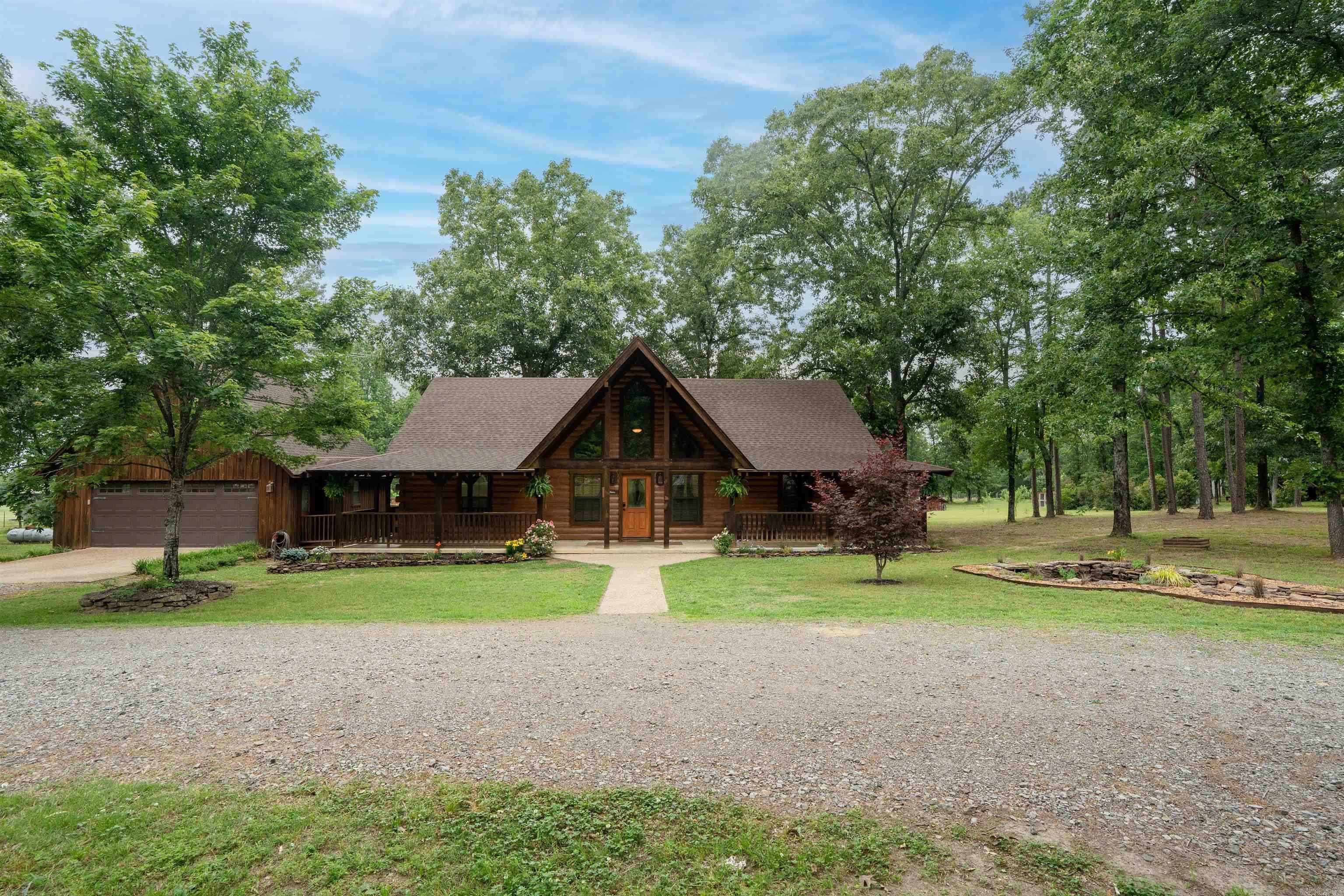 Custom built 1 owner home and you can feel that in every corner of this property. The Log home is laid out so well that no space is wasted. The living/dining & kitchen are all very open and there is a beautiful double sided gas log fireplace. Natural light flows through all the windows. The kitchen has so many pull outs and built ins plus custom rotating shelving in the pantry. The laundry room is off the kitchen and has a beautiful glass door.  The primary bedroom en suite has a jetted tub and separate shower. Laminate & tile floors and custom blinds on the windows. The property has a circle drive, a koi pond in the front yard, beautiful landscaping and the covered concrete wrap around porch connects to the beautiful deck and to the above ground pool and the detached double garage that also has a large loft. There is a stocked pond with a fishing dock, a pole barn, and a wired shop with a covered RV lean to and electric RV hookup. City water plus 2 wells are on the property. The 45 acres includes Ridings Lane and on that lane is a cabin that needs remodeled but excludes the minerals and a mobile home on 3/4 acre past that cabin. Such an amazing property. Agents see remarks.