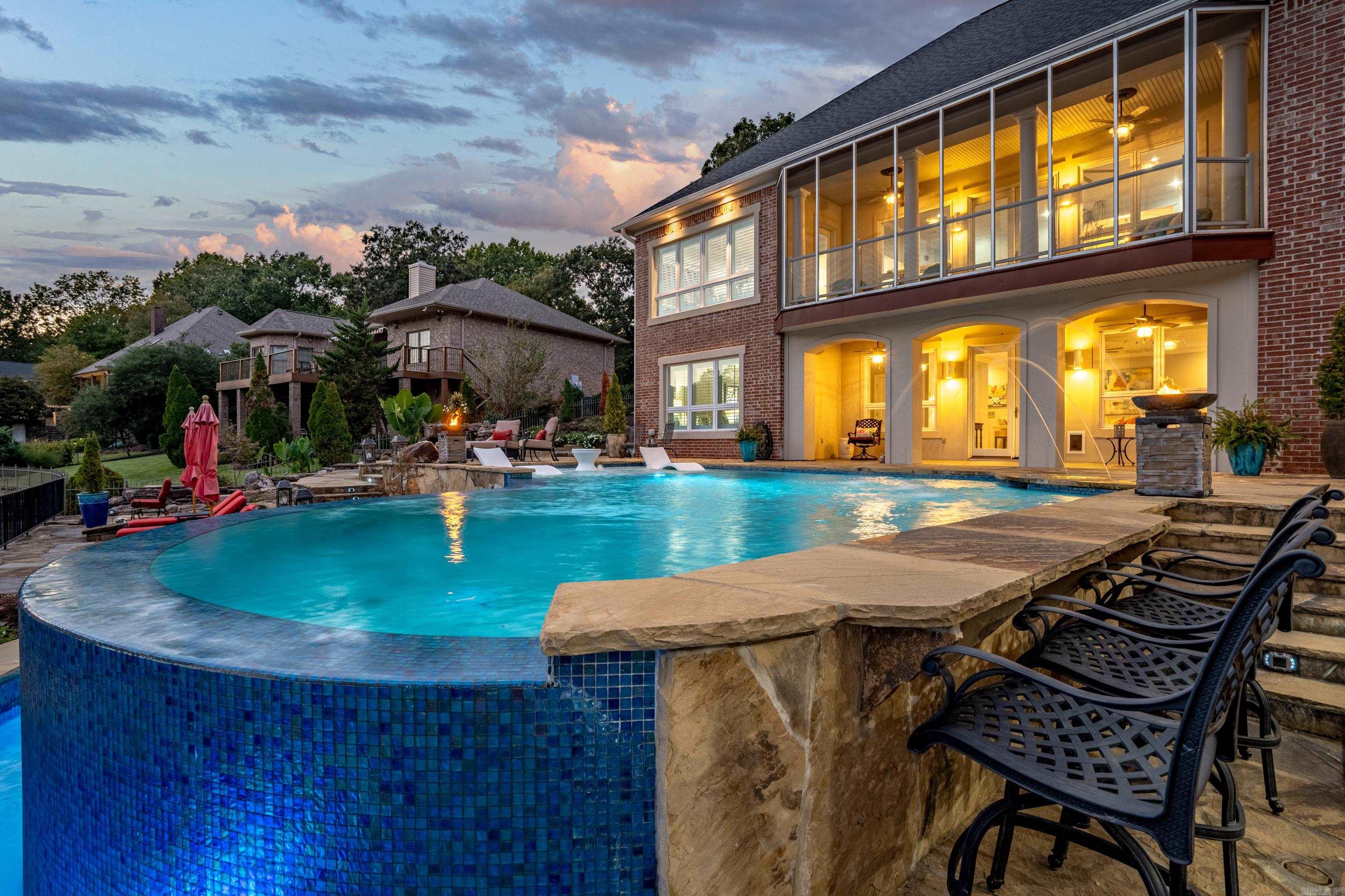 Experience luxury lakefront living at its finest! This custom-built lake home, in the highly sought-after Driftwood Point community, offers the ultimate resort-style experience right out your backdoor. Enjoy breathtaking lake views from nearly every room. Relax in your infinity pool with a swim-up bar overlooking the lake. Entertain in style with a full outdoor kitchen, cozy fire pit, and a tranquil waterfall feature that completes the backyard oasis. Inside, the open floor plan seamlessly blends indoor and outdoor living, perfect for hosting family and friends. The walkout basement adds even more entertainment space and convenience, leading right out to the water's edge. Enjoy your custom-built covered double boat dock with lifts and a jet ski dock. From its stunning design to its top-tier amenities, this one-of-a-kind lake retreat is truly an entertainer's dream, where everyday feels like a vacation.