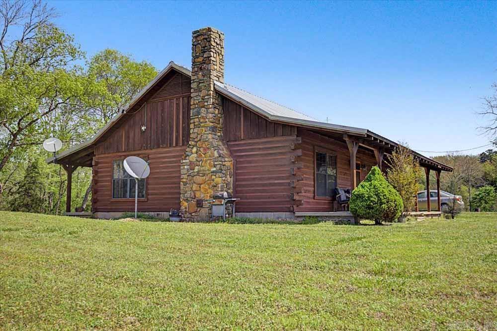 ONE OF A KIND! Rustic Log Cabin home with a covered porch on 25.78 acres near Mena, Arkansas with a woodburnings stove, 1200 square foot barn, a 2800 utility building, a pond, plus three small utility buildings. and a creek running alongside of the back of the property. The land has 882' of highway frontage and is about 1/3 timber, and 2/3's cleared area for agriculture (Pasture and/or crops).    It's less than 10 minutes from shopping and dining in Mena and Hackett.  This is your opportunity to live in scenic Western Arkansas in a beautiful log cabin, where you can sit back and relax or to raise some cows and horses and enjoy some gardening. Don't miss out. Schedule your viewing today.