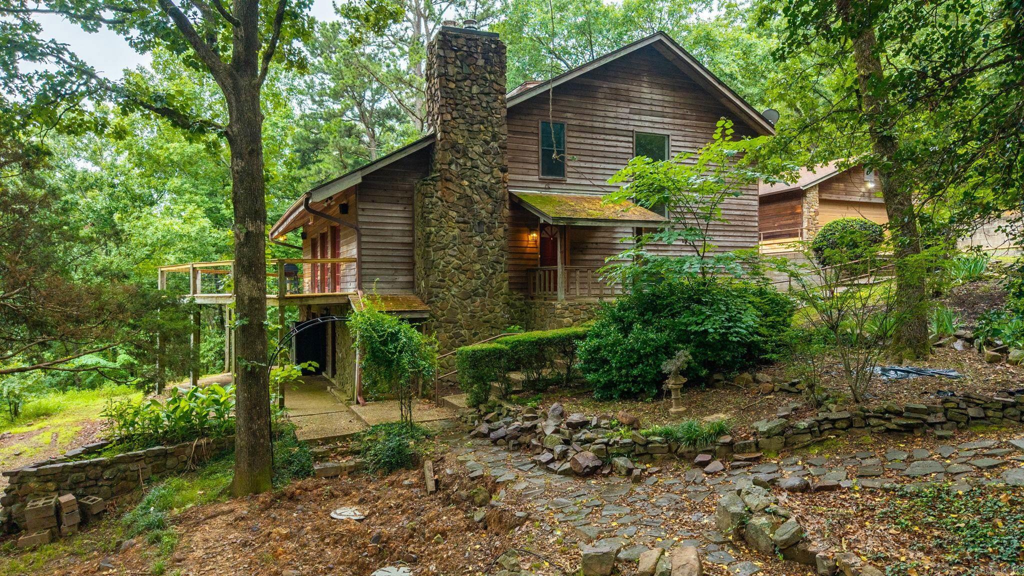Nestled on 5 private wooded acres, this custom log home offers breathtaking panoramic views of Lake Maumelle and the perfect blend of rustic charm and modern comfort. Inside, you'll find soaring vaulted ceilings, rich hardwood floors, and multiple French doors that open to expansive outdoor living spaces designed to showcase the scenery. The spacious kitchen and inviting sunroom create ideal gathering spaces, while the main-level primary suite features a walk-in shower, soaking tub, laundry room, and convenient half bath. Upstairs offers brand new HVAC ('26) for 3 bedrooms and a full bath. The walk-out lower level is perfectly suited for guests, multigenerational living, or entertaining, featuring a second kitchen, hearth room with Buck stove fireplaces, guest bedroom and bath, oversized second laundry room, and direct access to the covered patio through multiple French doors. Outside, terraced stone landscaping leads to a level yard framed by an arbor, creating a rare combination of usable outdoor space and natural beauty. An insulated workshop/garage provides ample room for hobbies, storage, or projects.