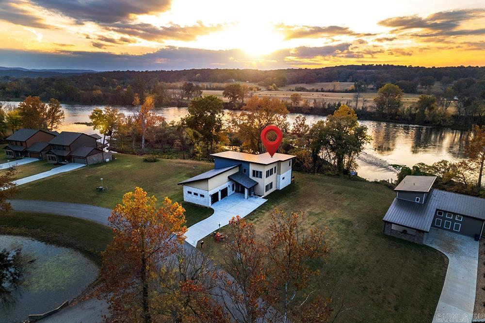 Striking modern architecture paired with a beautiful river backdrop creates impressive curb appeal. This exceptional 3-bedroom, 3.5-bath residence is thoughtfully designed w/ modern accents open-concept layout connects living, dining, & kitchen areas. The primary suite features handicap-accessible design, tiled shower, huge closet, and heated indoor therapy pool. Statement staircase leads upstairs to second living room with fireplace, 2 bedrooms w/ beautiful river views and walk-in closets, two full bathrooms, a spacious heated & cooled bonus room, and office space. The home includes a whole-house generator, dual high-efficiency HVAC units, gas fireplaces on both levels, and fiber internet. Additional highlights include 2-car garage, laundry room,  cargo elevator, low-maintenance deck, and city water/sewer services.