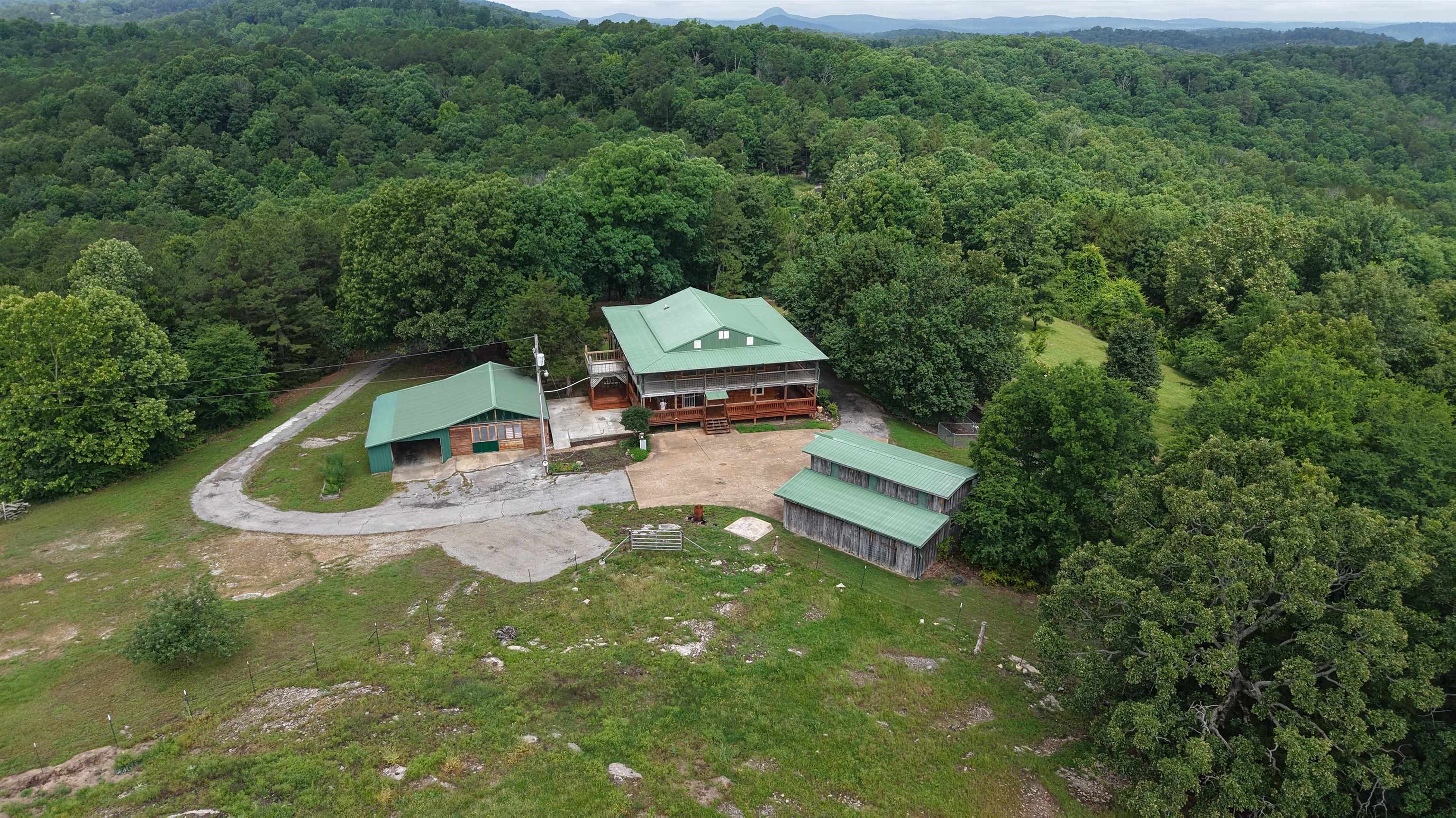 This 2,400 sq. ft. log home sits on 8 surveyed acres just off Hwy 9 South in the heart of the Ozarks. With mountain views and usable acreage, this property is well-suited for those looking to enjoy country living without giving up modern amenities. The two-story home features spacious living areas with large windows that bring in natural light and showcase the surrounding landscape. Interior highlights include walk-in closets, a walk-in pantry, on-demand water heater, natural gas, mini-split systems, city water, and septic. Outside, the covered wrap-around porch provides a comfortable space to relax and take in the views. There is also a designated area ready for a hot tub, making it easy to create your own outdoor retreat. The property is well-equipped for work or hobbies with two shops and an additional garage. One of the shops includes a car lift and large air compressor, offering a ready-made setup for mechanics, projects, or small business use. All appliances convey with the sale, making this home move-in ready. Priced at $329,000, this property offers a rare combination of acreage, functionality, and Ozark scenery.