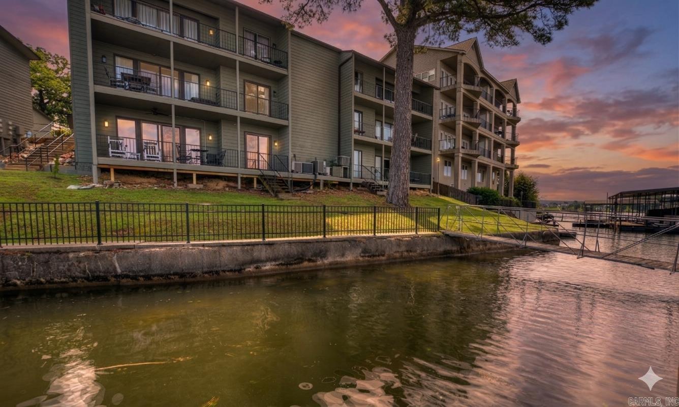 Experience the perfect blend of vintage charm and premier positioning in this pristine, lower-level end unit at The Landing. Established in 1983 on what is widely considered the best spot on the lake, this complex offers unmatched convenience by boat or car. Enjoy spectacular, wide-open views down the main channel and front-row seats to summer fireworks from an expansive patio. The unique outdoor space features an iron railing with a private gate opening to lush green space—perfect for pets and providing quick access to the water.  A big bonus is the included covered boat slip with lift, measuring an impressive 28 feet. This rare find accommodates larger watercraft that typical condo slips cannot. Inside, the meticulously preserved interior features original finishes in perfect condition. The efficient layout includes two bedrooms, two full bathrooms (including a primary suite), and an inviting family room with a fireplace. Residents enjoy a gated community with a lakeside pool, pickleball, and grilling areas. With the POA allowing short-term rentals, this unit is a fantastic investment opportunity or a nostalgic lakefront retreat.