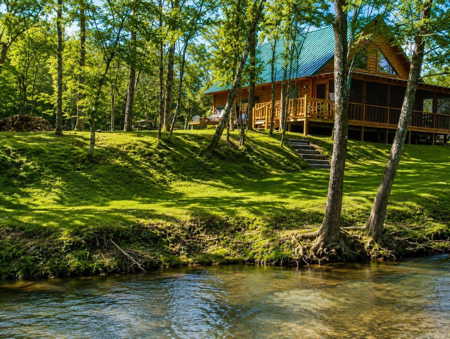 Charming log cabin nestled along the banks of Lick Creek in Norman, Arkansas. Currently operating as a successful vacation rental, with profit and loss statements available upon an accepted offer. In addition to the cabin, the property includes extra creekside land featuring RV hookups—perfect for expanding rental income or hosting guests. The cabin offers a warm and inviting layout with two bedrooms on the main level and a spacious loft upstairs. It is being sold fully furnished, making it truly turnkey. Enjoy peaceful creek views from the screened-in porch, which opens to a back deck with a seating area and hot tub. Beyond the deck, a fire pit and outdoor seating create the ideal setting for relaxing evenings by the water. Recent owner improvements include a new HVAC system, tankless water heater, refrigerator, fireplace insert, hot tub cover and heater, washer and dryer, and new water lines to exterior spigots. This unique creekside retreat combines rustic charm with modern upgrades and income-producing potential.