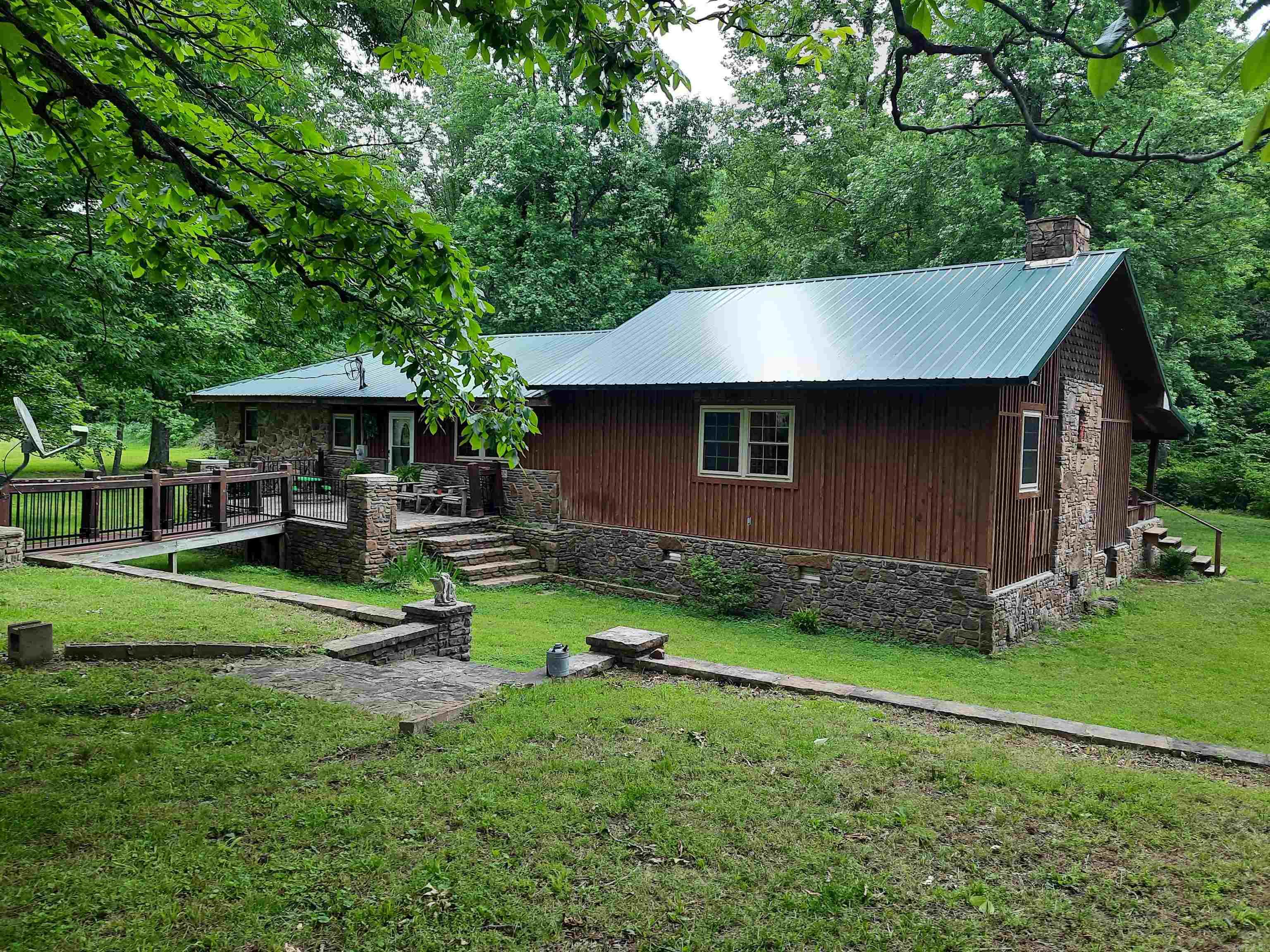 Escape to your own slice of secluded paradise, 20 serene acres, mostly wooded, but does offer some pasture area also, perfect for hunting, recreation or peaceful living. Plenty of room for livestock, gardening, offers large shop, barn, pond with fishing dock, plus a charming playhouse for the kids. Home has a big covered front porch, and a very beautiful back porch with custom stonework, also included are stone walkways and if this isn't enough, a custom outdoor kitchen complete with BBQ, and pizza oven, you can sit at the bar and enjoy visiting and entertaining while listening to the beautiful water feature.  Inside you will find 2 bedrooms, 1 bath that offers a large soaking tub plus custom walk-in shower, kitchen offers lots of cabinets and counter space, eat at bar, large dining area and you will love the great room, open beams, vaulted ceiling, FP, and so much more.  This property is one of kind, a must see to appreciate.
