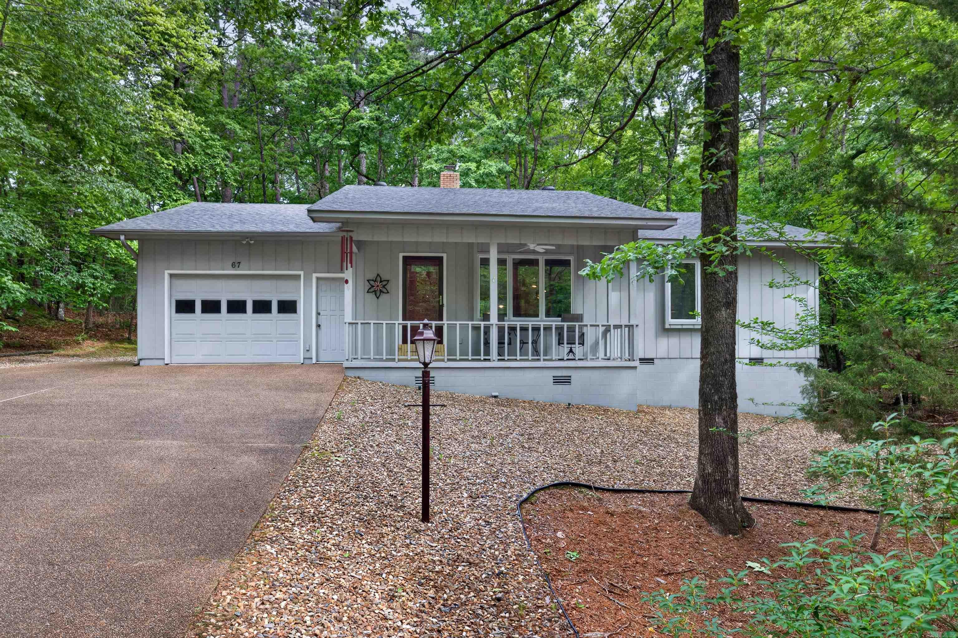 Inviting front porch welcomes you to this immaculate home surrounded by trees for ultimate privacy.  Living room features large picture window, bult in shelves and wood burning stove.  Kitchen cabinets are a very nice upgrade with pull outs and lots of storage plus an island.  Kitchen connects to laundry with matching cabinetry for additional storage, sink and desk area.  Dining room overlooks wooded back yard and spacious deck.  Two bedrooms complete the interior of this charming home.  Primary has private bath with walk in shower and full wall closet.  Second bedroom has access to second bath. Both bedrooms are exceptionally large.  Garage includes door opener, workshop area and opens to deck.  Very well loved home. Hot Springs Village boasts 9 golf courses, 11 lakes, pickleball, hiking trails, white sand beach, tennis, fitness center, indoor and outdoor pools and so  much more.  Half an hour from Hot Springs or Benton and one hour from Little Rock airport.. HSV has one time $2000 buy in for new residents.