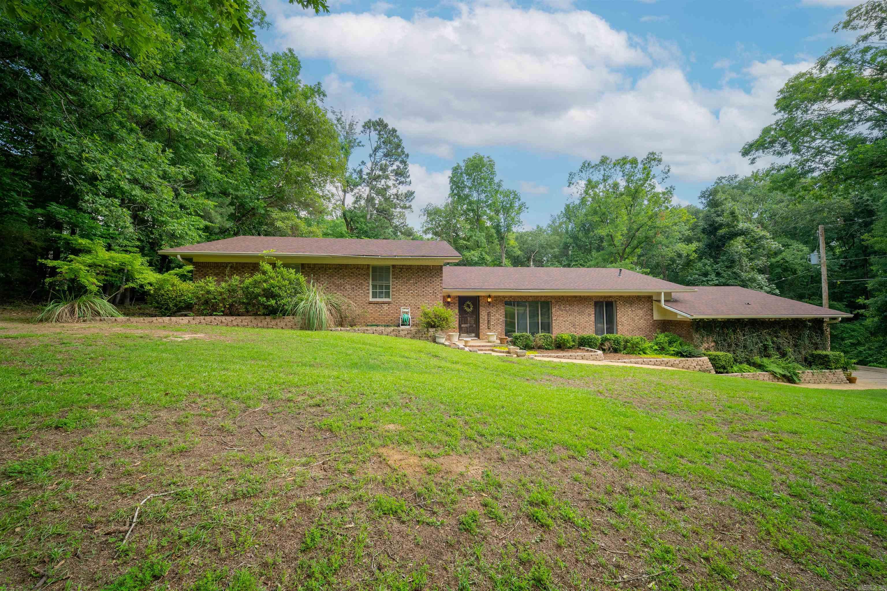 Welcome home to this stunning 2,100 square foot traditional brick home with a modern flair, perfectly situated on 4.42 beautiful acres just outside the city limits. Offering the ideal blend of privacy and convenience, this move-in-ready property features 3 spacious bedrooms and 2.5 baths designed for comfortable everyday living. Inside, you'll find a thoughtfully designed floor plan with a separate dining room, dedicated laundry room, convenient half bath, and a large walk-in pantry. The kitchen is sure to impress with granite countertops, ample cabinetry, and updated flooring that flows throughout the home.The inviting living area showcases a cozy wood-burning fireplace, while the heated and cooled sunroom provides the perfect place to relax year-round, complete with a stunning wood-planked ceiling and views of the surrounding property. The spacious primary suite offers a luxurious retreat with a large walk-in closet and an oversized walk-in shower in the master bath. Bonus: roof is only 2 years old! You will appreciate the large shop featuring electricity and three roll-up doors—ideal for hobbies, storage, equipment, or a home-based business.