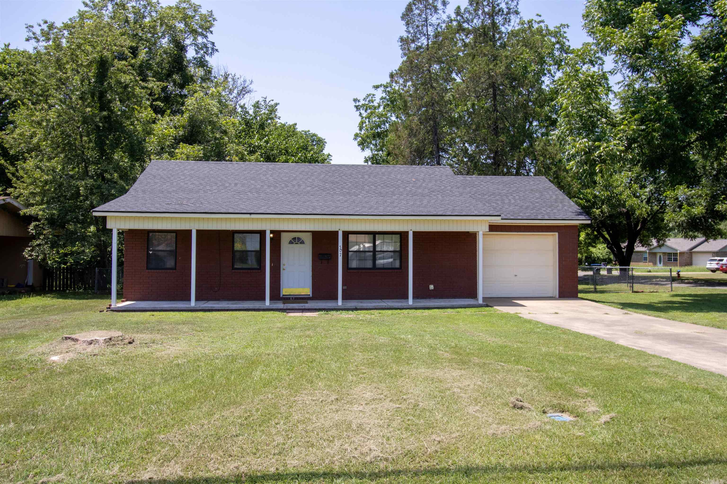 Charming one-level brick home in the heart of Clarksville, offering 3 bedrooms and 2 full baths in 1,044 sq ft. New luxury vinyl plank flooring runs throughout, paired with fresh paint and ceiling fans in every room. The eat-in kitchen features wood cabinetry, laminate countertops, and a full appliance package including a dishwasher, electric range, microwave, and refrigerator. The primary bath was tastefully updated with a walk-in shower and matte black fixtures, while the second full bath offers a classic vanity with a wall-mounted medicine cabinet. Outside, enjoy a covered front porch with white columns, an attached one-car garage, and a concrete driveway. The level corner lot includes a fully fenced backyard shaded by mature trees, plus a storage building for extra space. Located in the Clarksville school district with public water, sewer, and low annual taxes, this move-in-ready home is a great fit for first-time buyers, downsizers, or investors. Schedule your showing today!