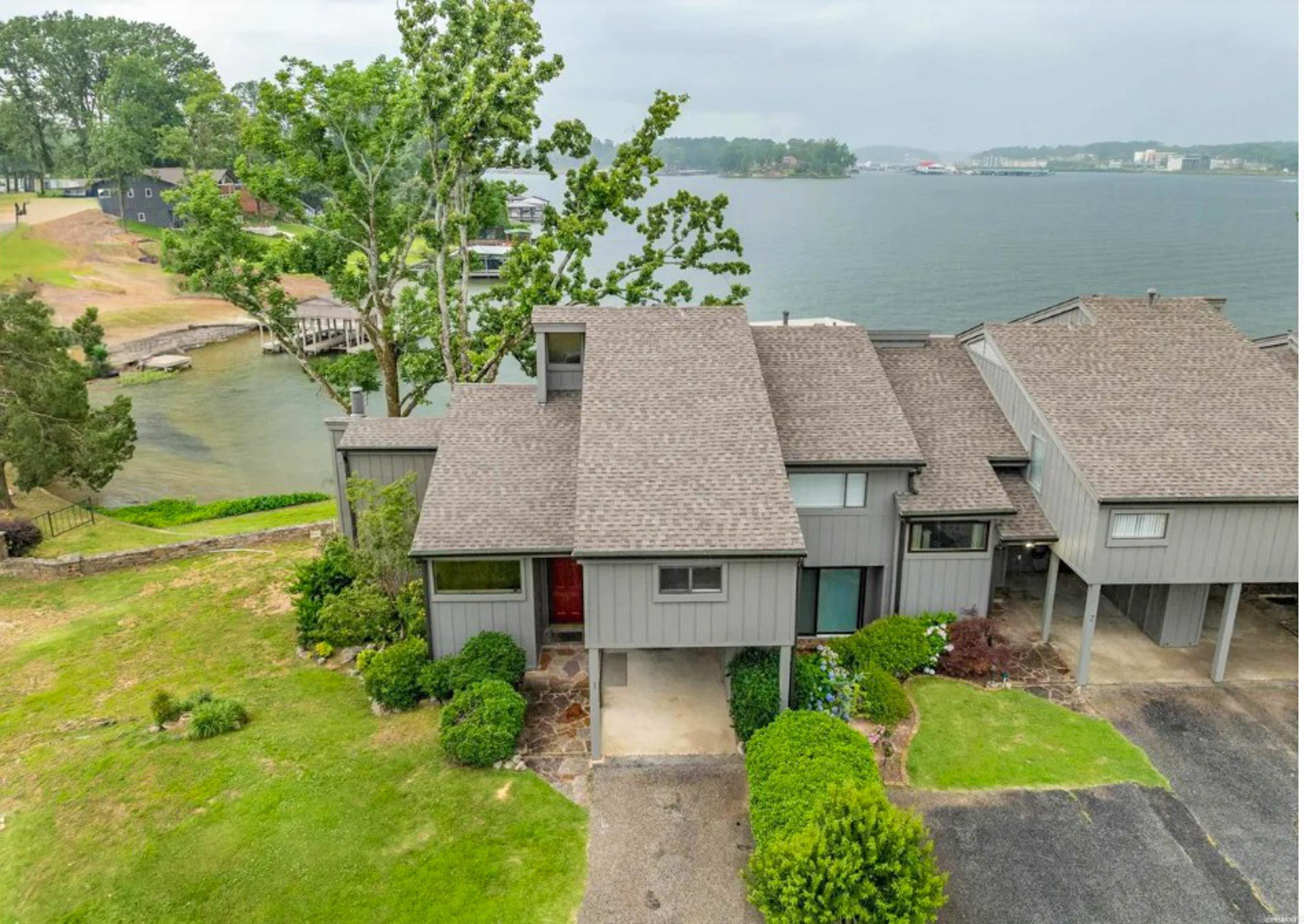 **Lake Hamilton Townhome with Main Channel Views in Long Island Bay**  Enjoy panoramic Lake Hamilton views from this updated townhome in the gated Long Island Bay community. Unit A-1 offers 2–3 bedrooms, 2.5 baths, and flexible living space designed for both full-time living and weekend lake enjoyment.  Inside, vaulted ceilings with exposed wood beams and a rock fireplace create a warm, inviting atmosphere. The updated kitchen features new appliances and flooring, while recent improvements throughout the home include hardwood flooring, new windows, interior and exterior paint, blinds, front door, and primary bedroom sliding door. A bonus room provides additional space for guests, a bunk room, office, or hobby area.  Step outside to a spacious deck overlooking the main channel, ideal for relaxing or entertaining. Property includes a covered boat slip with lift in deep water, plus carport parking and storage.  Additional updates include a new roof in 2024. HOA amenities include a lakeside pool, gazebo, water, exterior maintenance, and insurance. Conveniently located near shopping, dining, and all that Lake Hamilton has to offer. Upgrades listed in agent remarks