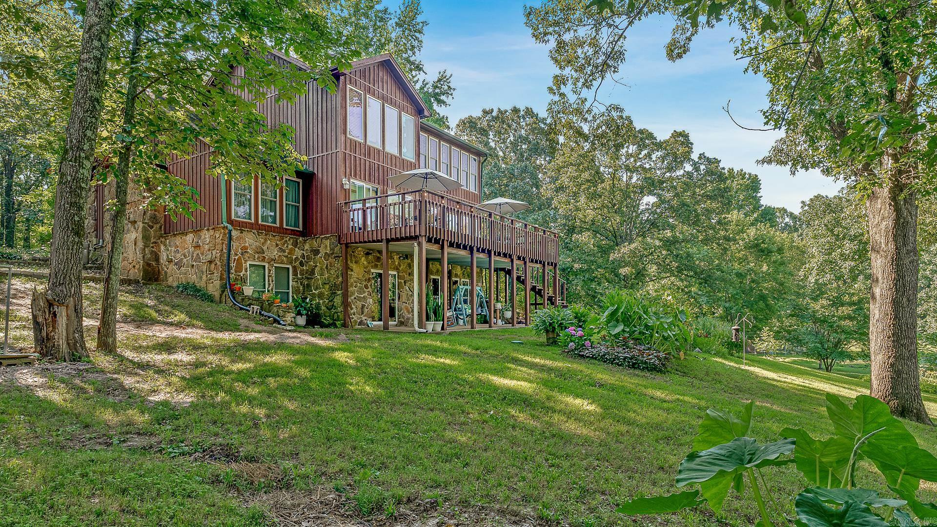 56.86 -ACRE SELF-SUSTAINING COMPOUND WITH PRIVATE LAKE, BARNS & ORCHARDS 5BR/3BA CYPRESS & STONE HOME – OFFERED AT $649,500 Escape the city and enjoy turnkey country living on this fully equipped 56-acre working homestead, designed for self-sufficiency, privacy, and multi-generational living. Set deep within the property for seclusion and security, the rugged cypress-and-stone home offers approx. 4,265 sq ft with 5 bedrooms, 3 full baths, a gas fireplace in the great room, and a massive stone fireplace in the cedar-lined full basement. Walls of windows in the great room and two sunrooms frame panoramic views of the private fishing lake and secondary livestock pond, with a second-story deck and primary bedroom sunroom also overlooking the water. Open, level lawns create a visible, safe area for kids and pets, surrounded by woods and pasture. The land is ready for food production with 20-year-old pecan trees, assorted fruit trees, grapevines, persimmons, and three garden sites. Cypress barns, sheds, a poultry coop, private lake, livestock pond, and 1-mile trail complete this self-sustaining retreat with abundant wildlife and room to expand, explore, and truly unwind.