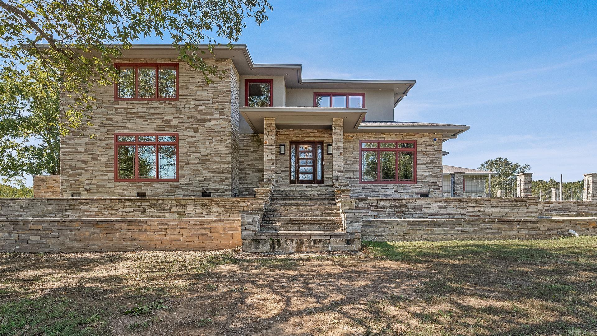 Set on 26 scenic acres, this stunning modern prairie–style home is a showcase of craftsmanship, detail, and timeless beauty. Every element was thoughtfully designed—from the milled black walnut trim to the heated tile floors and inviting wood-burning fireplace. The gourmet kitchen impresses with quartzite and Corian countertops, an oversized island, double fridge, warming drawer, pantry freezer, and crushed ice maker. The primary suite offers radiant heat floors, a soaker tub, dual sinks, an in-suite washer and dryer, and a spacious custom closet. A floating steel-framed staircase highlighted by a stained-glass chandelier leads to a second living space with fireplace and a full bar featuring a wine cooler, sink, and ice maker. The fully finished heated and cooled garage also includes a snow-melt system. Outside, enjoy a resort-style inground pool with spillover spa, a two-bedroom guest house with full kitchen and dual living areas, a large shop, and a picturesque pond with fountain—an extraordinary blend of luxury, comfort, and craftsmanship.