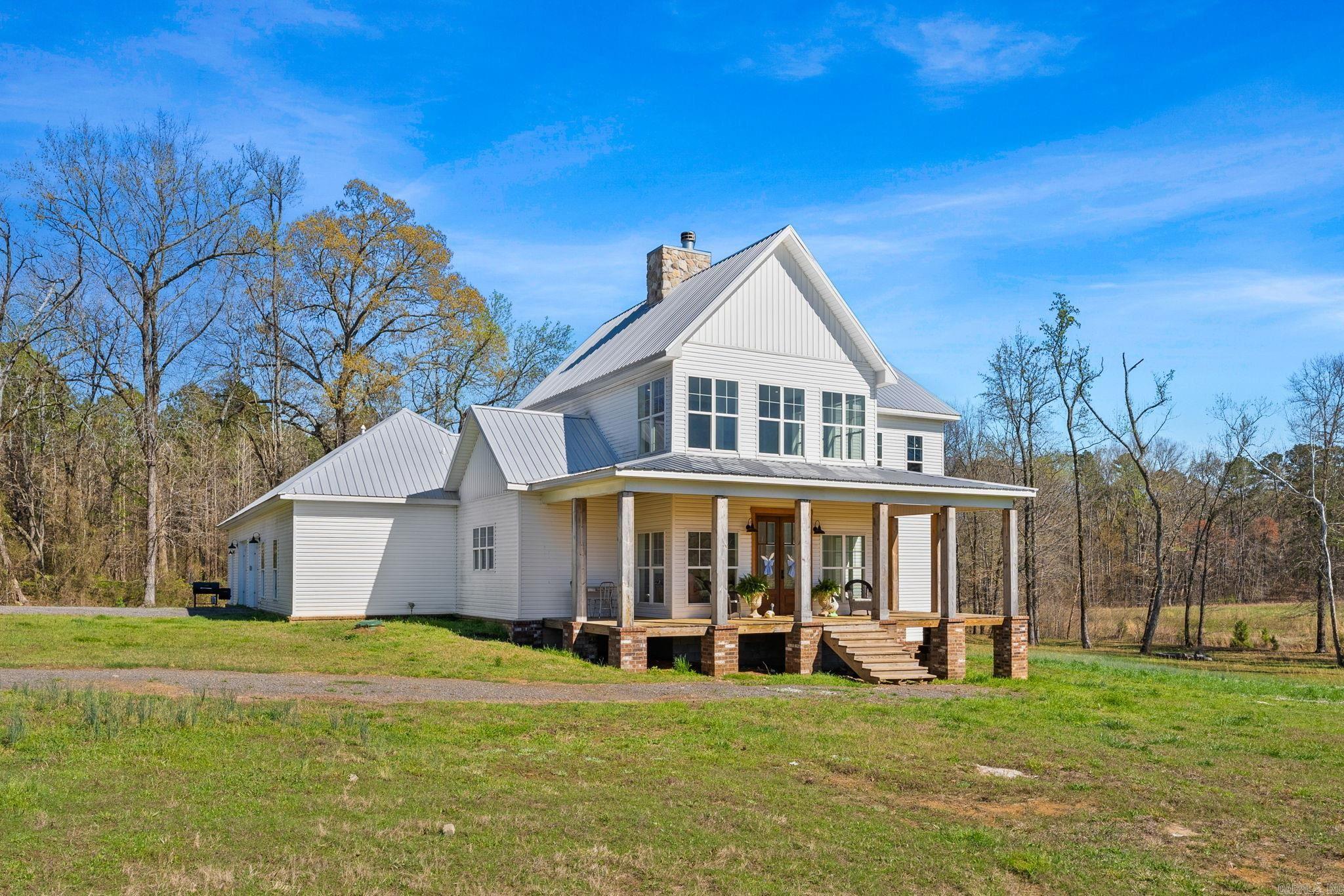 Welcome to your private country oasis! Nestled in an exclusive gated community in Mayflower, this stunning 3,000+ sq ft modern farmhouse sits on 20 picturesque acres complete with a meandering creek. With wide-open spaces, there is endless potential for a future barn, horses, or livestock.  Inside, soaring two-story ceilings and crisp white shiplap walls beautifully frame the magnificent floor-to-ceiling stone fireplace. Hardwood floors flow seamlessly into the open-concept chef’s kitchen, boasting a large island, elegant countertops, and a custom wood range hood.  The meticulous floor plan features 4 beds and 3.5 baths. The main level includes a luxurious primary suite with a spa-like bath and massive closet, plus a second en-suite bedroom, walk-in pantry, and guest half-bath. Upstairs offers two generously sized bedrooms with walk-in closets and a shared full bath, connected by a balcony overlooking the stunning living area below.  Complete with a durable metal roof, covered porches, and an oversized attached garage with extra storage. A rare opportunity for premium Arkansas country living!