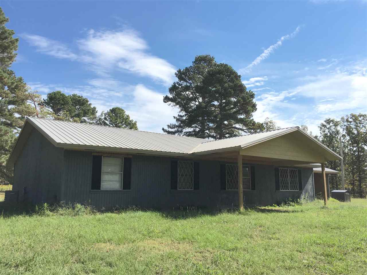 New Metal Roof, remodeled bathrooms, new flooring in living areas! Private location, on 5 acres of open land. Huge potential with this property. Wood burning stove, 2 living areas and separate utility room too! Carport and outbuilding as well.