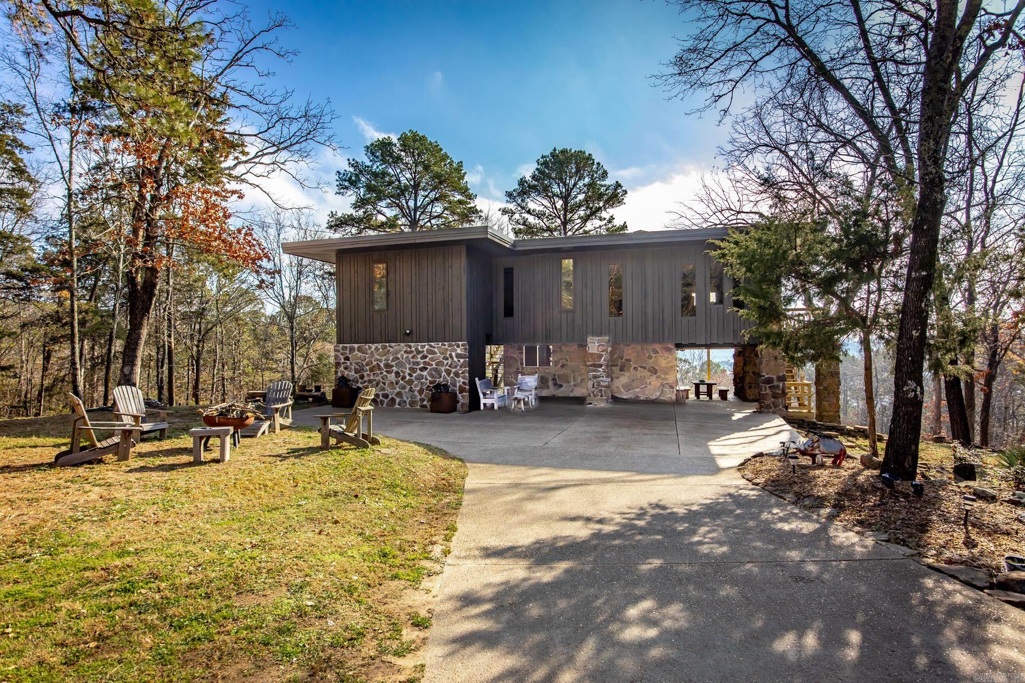 Stunning Mid-Century Mountain Retreat! Nestled among the trees and perched high above with sweeping panoramic lake & mountain views, this architecturally unique home blends elegant mid-century design with timeless natural elements. Striking organic architecture: Clean horizontal lines, expansive, floor-to-ceiling windows, natural stone walls, & extensive woodwork blend seamlessly into the landscape.Spacious wrap-around deck: Perfect for soaking in breathtaking sunrises & sunsets or entertaining with unrivaled vistas. Vaulted exposed-beam ceilings, stone accents, & abundant light create a warm, inviting atmosphere. Cozy interior with flagstone & wood floors evoke a private mountain lodge ambiance. This one-of-a-kind property is ideal as a full-time residence, vacation home, or short-term rental. Don’t miss your chance to own a rare blend of organic architecture rustic comfort in a truly spectacular natural setting! Expansive windows & views, Indoor-outdoor living. This home features a geo-thermal heat and air unit which are very energy efficient.  There is an additional septic system to add another guest house/building. See agent remarks.