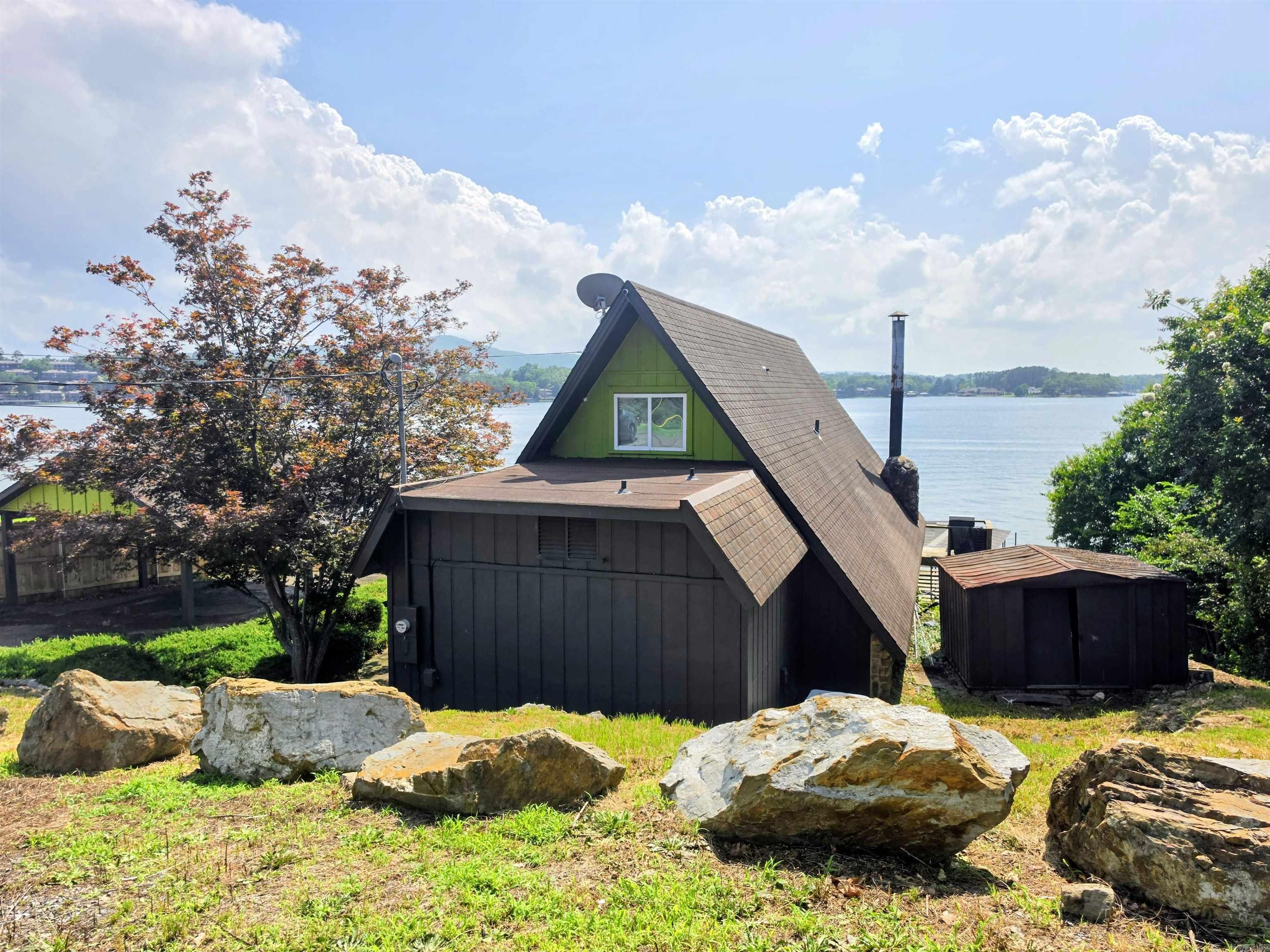 50K Down! Owner will finance! Let your lake house pay for itself! Fully furnished and no license needed, you can start your STR business as fast as we can close it! Guests will experience breathtaking Lake Hamilton Views from this stunning Mid-Century A-Frame Lakefront Home, which could be a duplex! The Main A-Frame features 2 Spacious Bedrooms, 2.5 Baths, And A Light-Filled Loft and Living Area that opens onto a deck with Panoramic Lake Views. The Lower 1 Room Studio offers a Charming Efficiency with Kitchenette, Full Bath, and Private Patio to double the rental income, or rent as 1 unit for larger parties. Nestled On an Island off Central Avenue on the Main Channel, this Rustic-Modern Gem combines Timeless Architecture with Lakeside Luxury and a view that will WOW you! Guests will enjoy the Private Two-Stall Dock with Lift and Water Slide for Endless Summer Fun! (Repairs will be made before closings with acceptable offer.) Come get creative with this one and make an offer today!