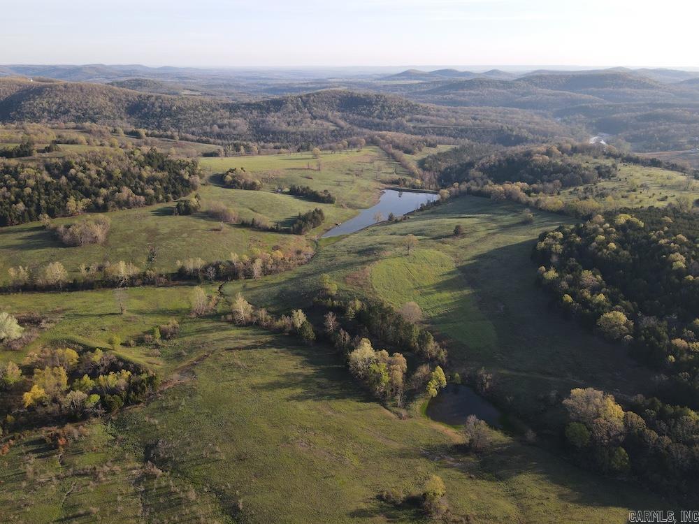 If you’ve been searching for a once-in-a-lifetime Ozark property, this is it. Tucked at the end of a gravel county road behind a deeded easement, 830+ private acres unfold in complete seclusion. Perched high on a ridge, the custom two-story home overlooks rolling valleys and distant mountains, with a massive deck made for sunrise coffee and spring gobbles. Large windows, an updated kitchen, fireplace, finished basement, and three-car garage blend comfort with practicality. The home sells furnished and includes ATVs, deer stands, and feeders. A large shop with living quarters provides ample storage for equipment and ranch needs. The land is gently rolling with 3+ miles of trails, established food plots, mature timber, pasture, and a proven wildlife management plan producing trophy whitetails and abundant turkey. Creeks, springs, and a fully stocked five-acre lake complete the setting. This isn’t just acreage—it’s a turnkey Ozark legacy built for generations.